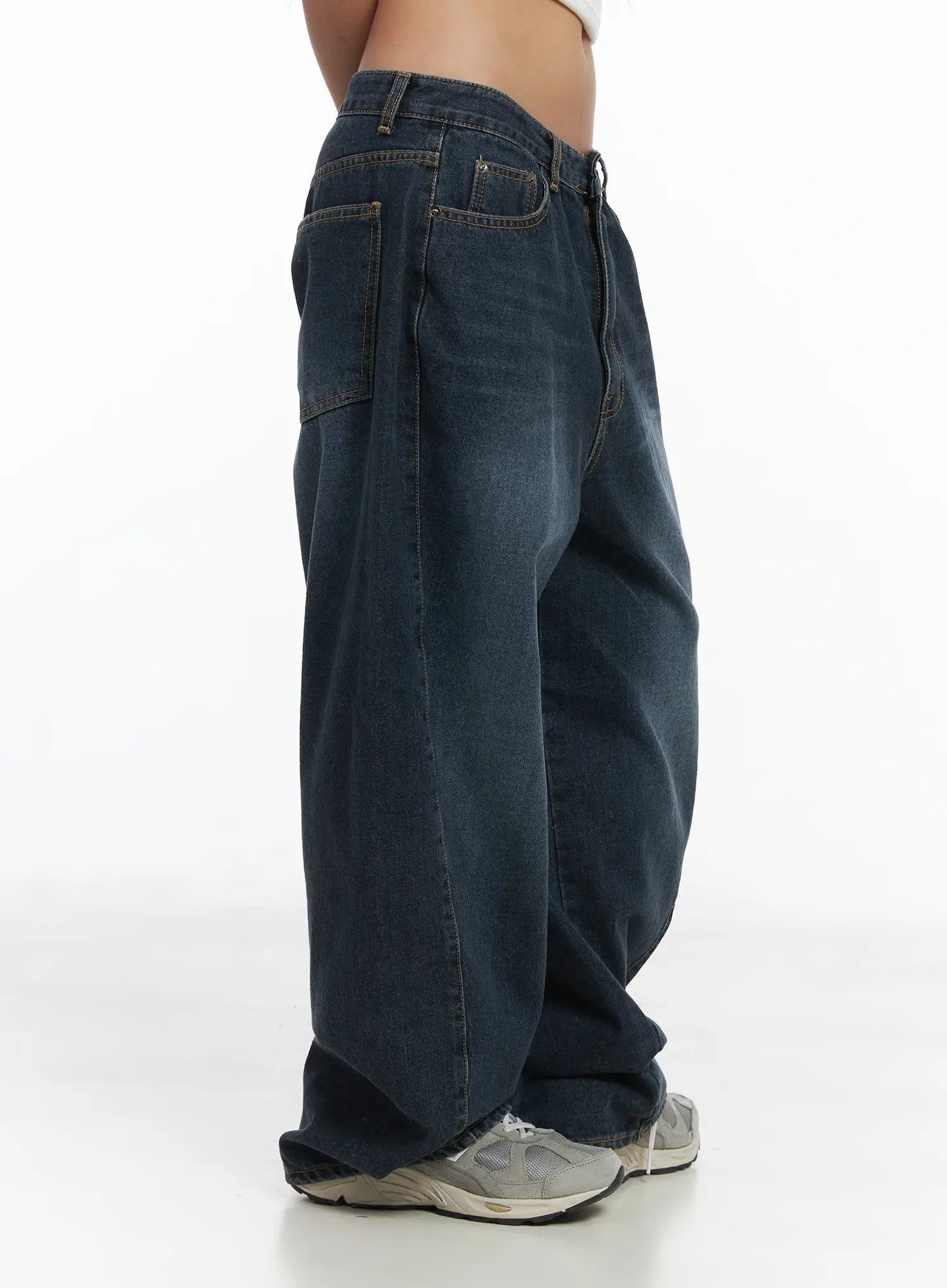 Everly Wide Leg Jeans CJ513 in dark blue, side view close-up on model, wide-leg washed cotton denim with visible side seam and utility pocket detail, paired with grey sneakers.