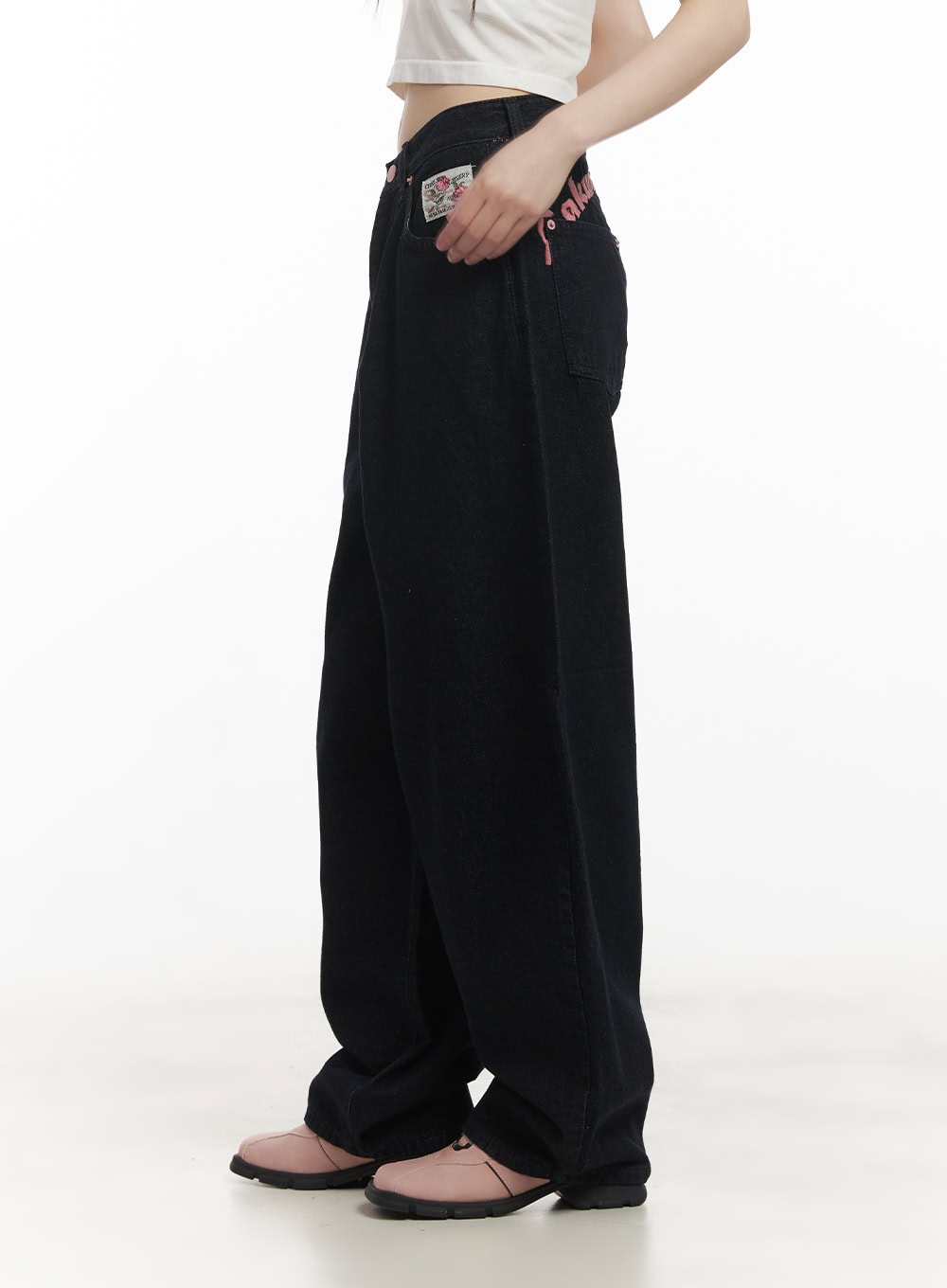 Dory Embroidered Baggy Jeans CF518 in dark blue, side view on model, wide baggy denim leg with pink embroidered lettering at waist and floral patch label visible.