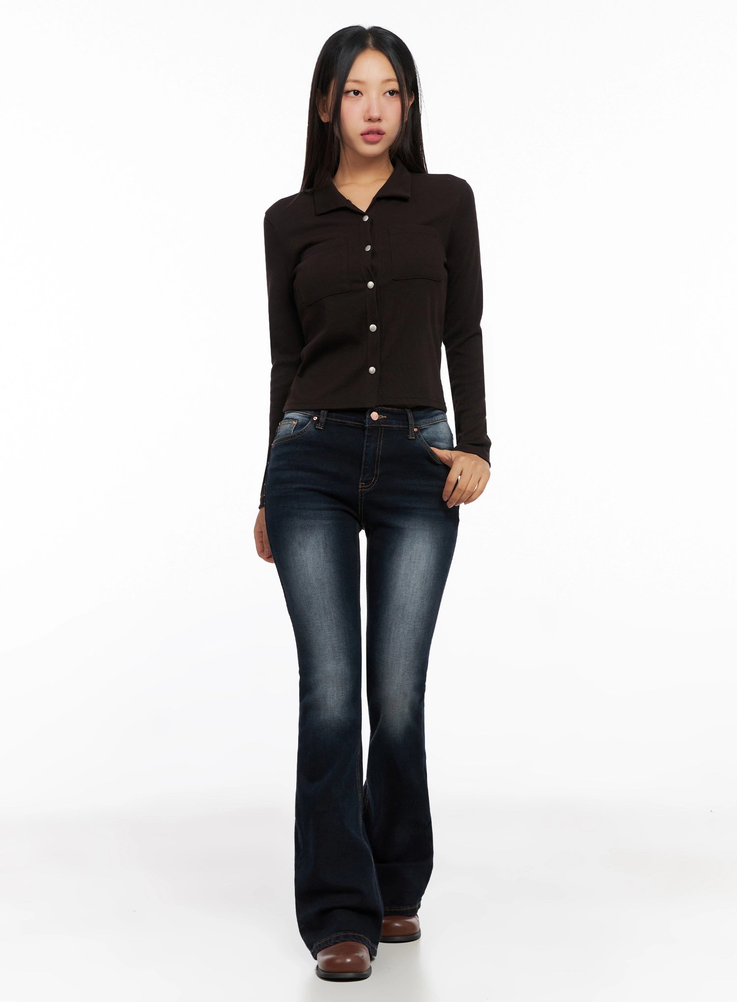 Aliyah Mid-Rise Hip Pad Flared Jeans IG528 in dark blue, front full-body model shot standing straight, washed denim with flare leg, layered with dark brown fitted knit shirt, brown boots.