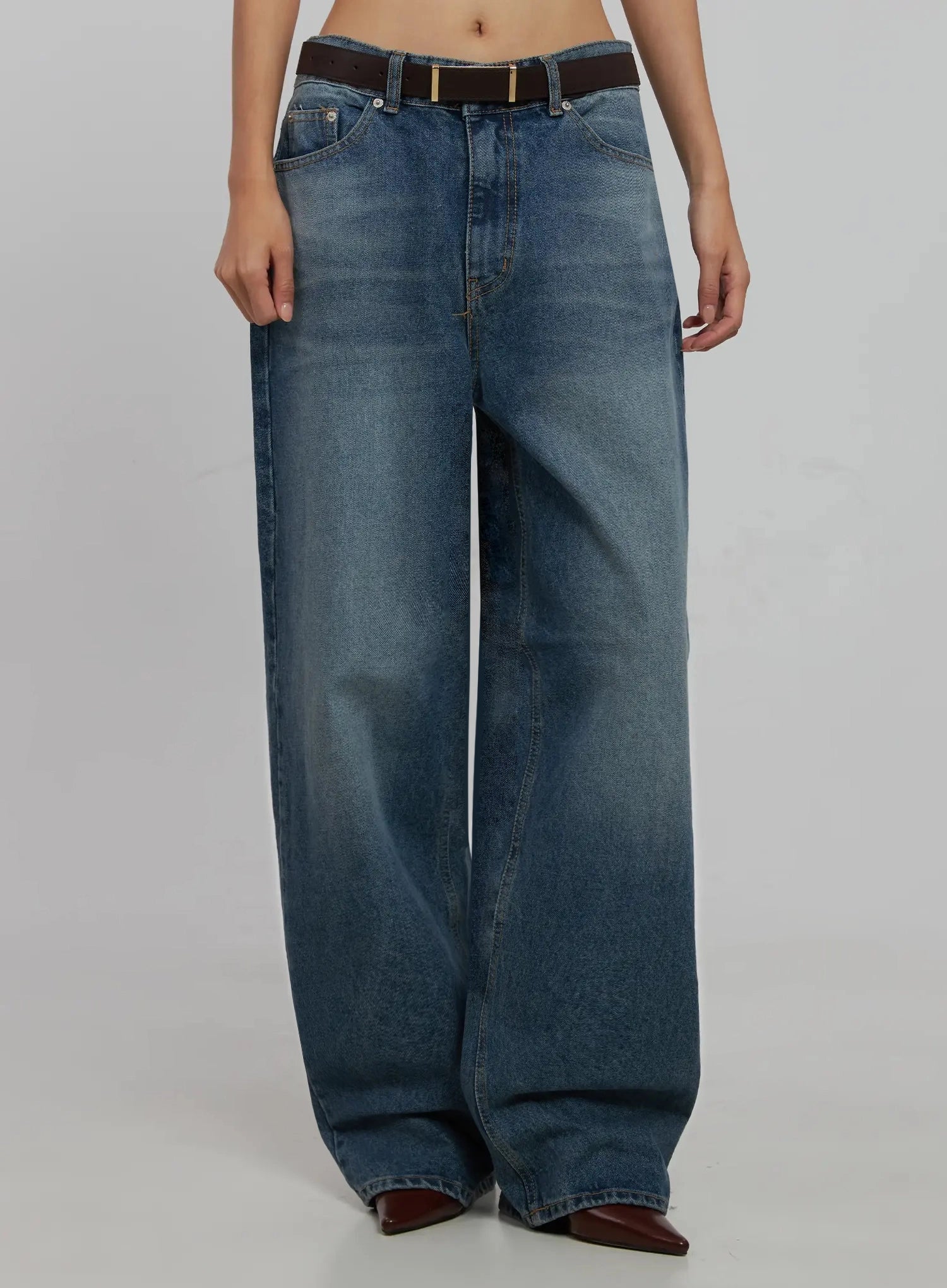 Akira Wide Leg Jeans IJ508 in blue, front view cropped at torso on model, relaxed wide-fit washed cotton, low rise with brown leather belt, burgundy boots.
