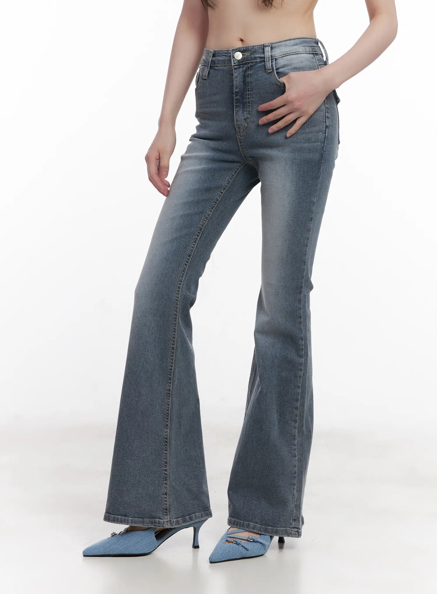Soyeon Flared Jeans with Hip Pads CU520 in dark gray, front close-up on model from waist to ankle, washed denim with button fly, slim hip fit and wide flared hem, blue kitten-heel mules.