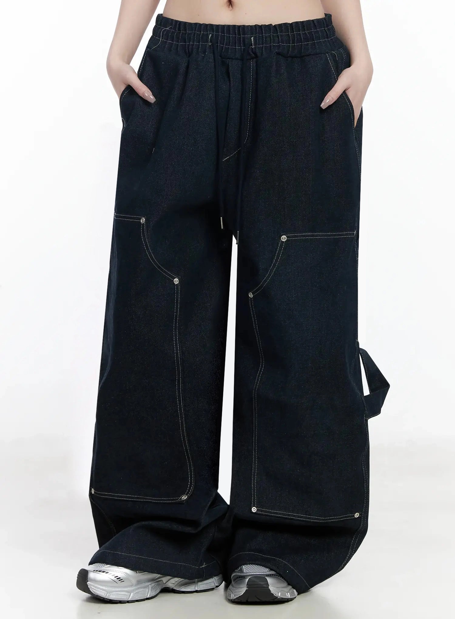 Ashlyn Carpenter Wide-Leg Jeans IJ528 in dark blue, front mid-shot on model, hands in pockets, elastic drawstring waist, curved carpenter pocket seams with rivet accents, wide cotton leg.