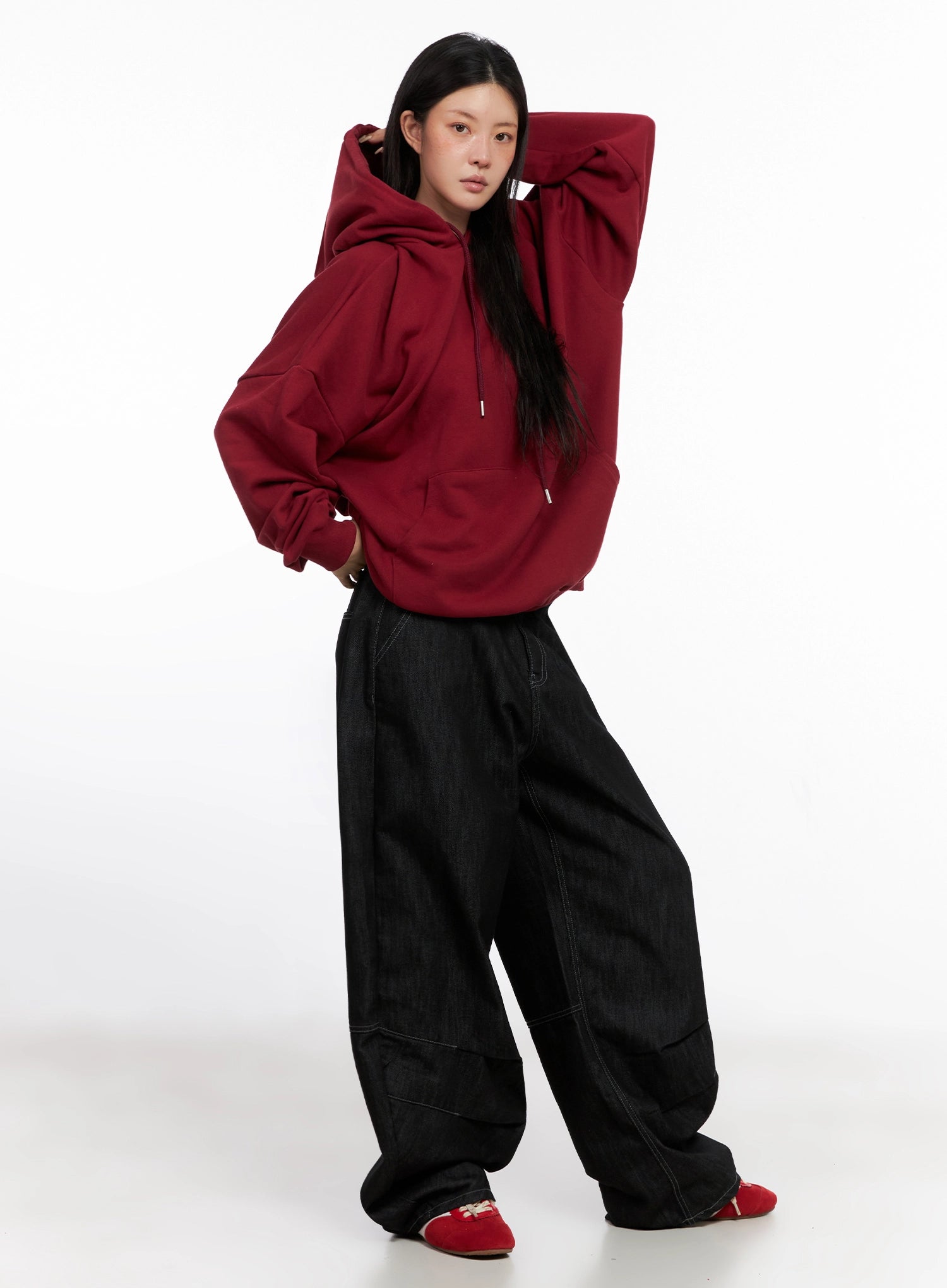 Leyla Pin-Tuck Wide-Leg Jeans IS515 in black, three-quarter front on model in red hoodie, dynamic pose with arms raised, street-style wide-leg cotton denim silhouette.