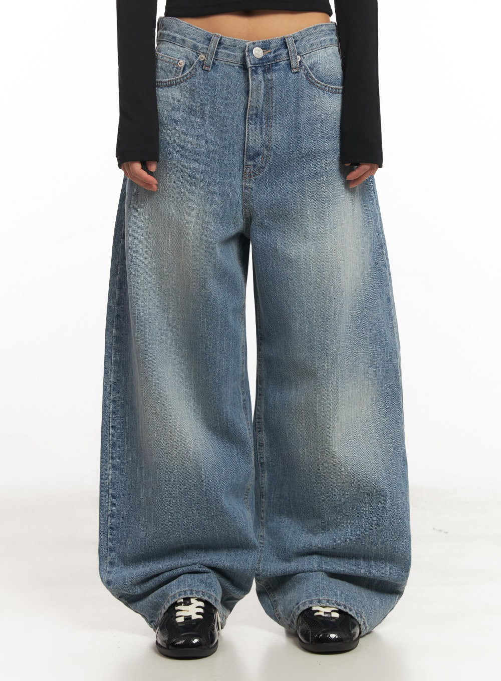 Yvette Washed Baggy Jeans IA517 in light blue, waist-to-hem front close-up on model, low-rise V-cut waistband and oversized wide leg with heavy fading, styled with black long-sleeve crop top and black loafers.