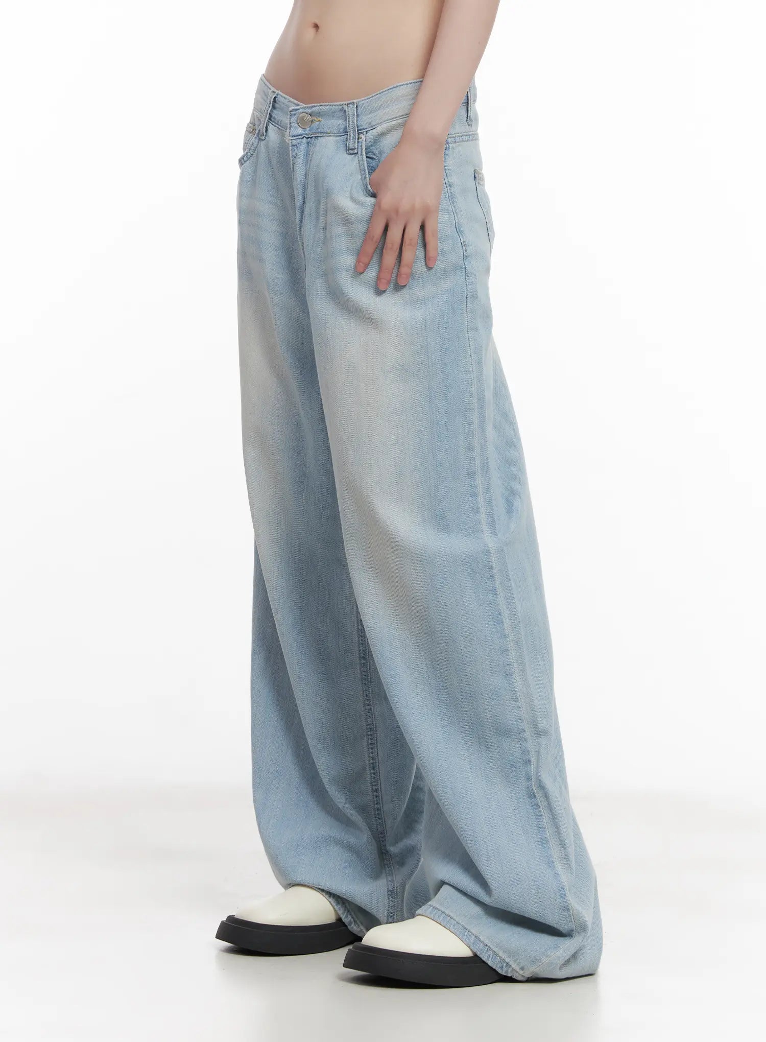 Garam Washed Wide-Leg Jeans CU518 in light blue, side close-up on model, low-rise waistband with button fly, hand in pocket, wide pooling leg in washed cotton denim.