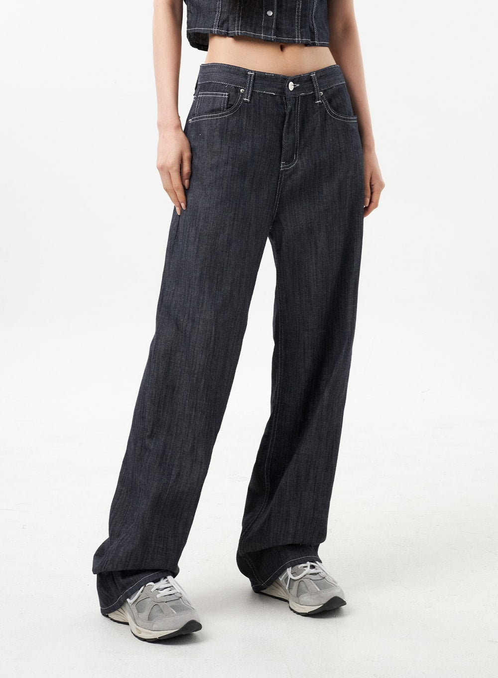 Low Rise Wide Pants CU312 in dark grey, waist-to-hem front close-up on model, low-rise waistband with contrast white stitch front pockets and button fly, wide leg draping over sneakers.