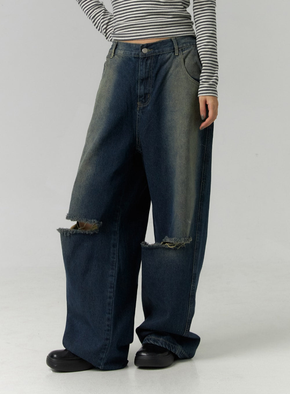 Destroyed Washed Wide Leg Jeans CN324 in dark blue, front mid-body close-up on model, highlighting low-rise button waistband, side pocket, and oversized ragged knee rips with frayed edges on washed denim.