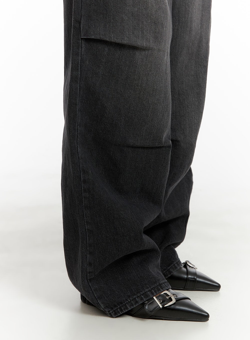 Pintuck Washed Wide Leg Jeans CA403 in Black, lower leg close-up on model, wide hem pooling slightly over black pointed-toe buckle flats, pintuck fold detail on outer thigh visible in washed denim.
