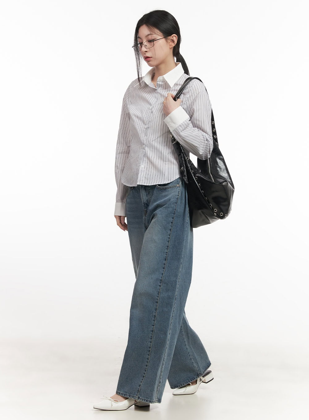 Andrea Wide-Leg Jeans CF514 in blue, side walking shot, model carrying black studded bag, wide-leg washed denim, full length visible, paired with striped shirt and white mules.