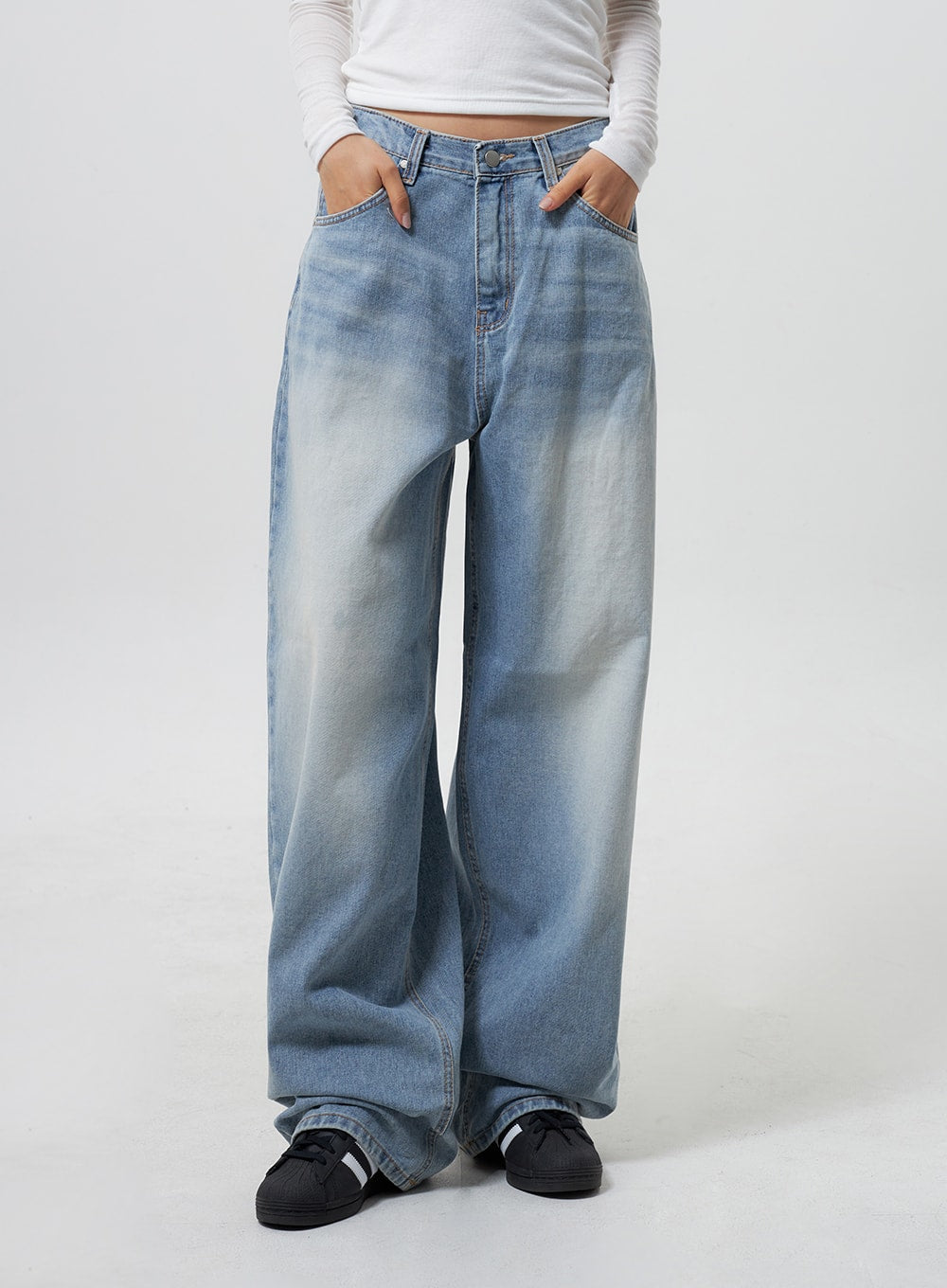 Low Rise Baggy Jeans CY324 in light blue, front mid-section close-up on model, low-rise waist detail with angled front pockets, faded wash cotton denim, wide-leg fit, white crop top visible.