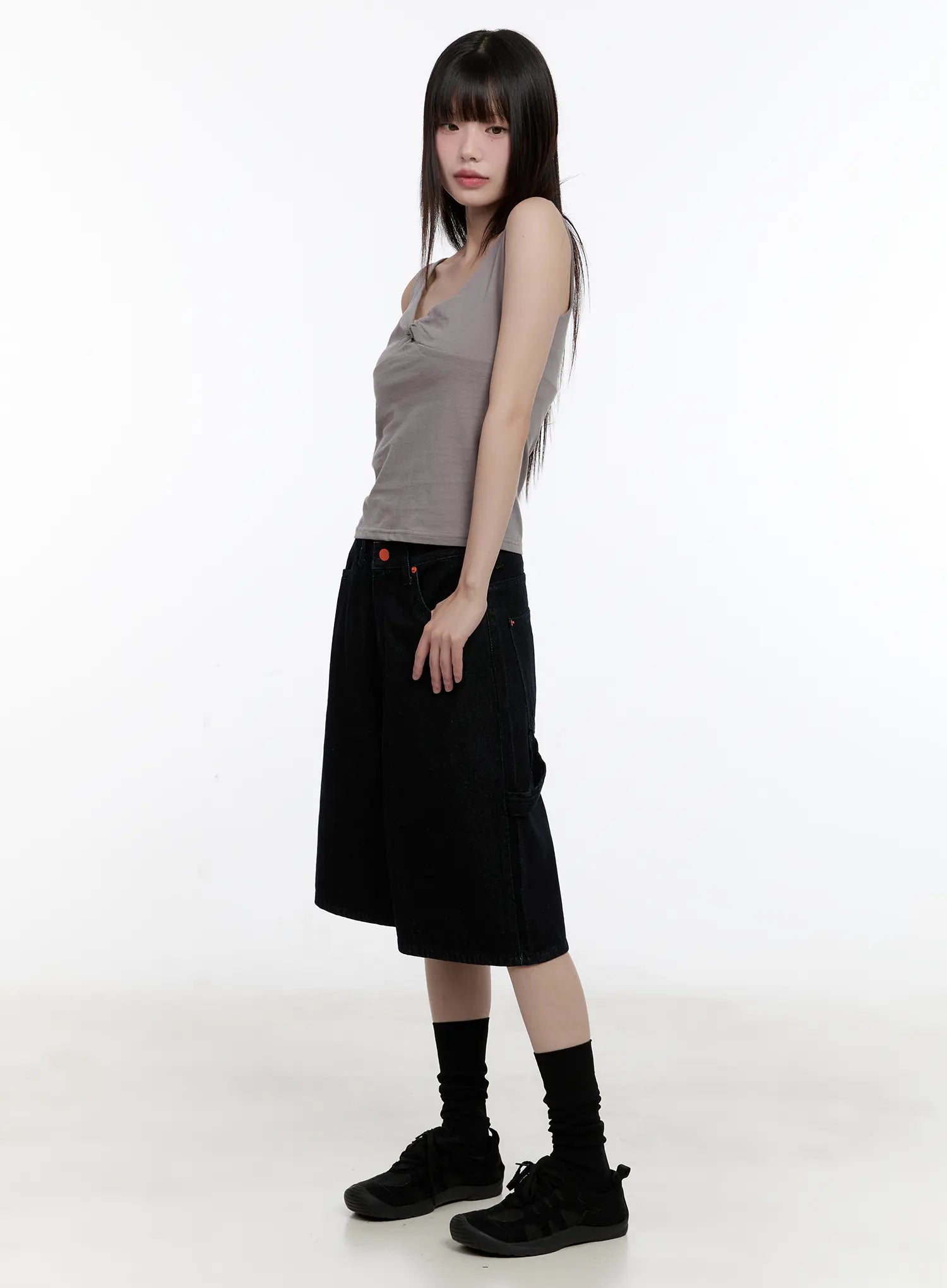 Red Text Graphic Embroidered Jorts CL504 in black, 3/4 side view on model, loose wide-leg cotton denim, half length, hand in pocket, paired with gray sleeveless top.