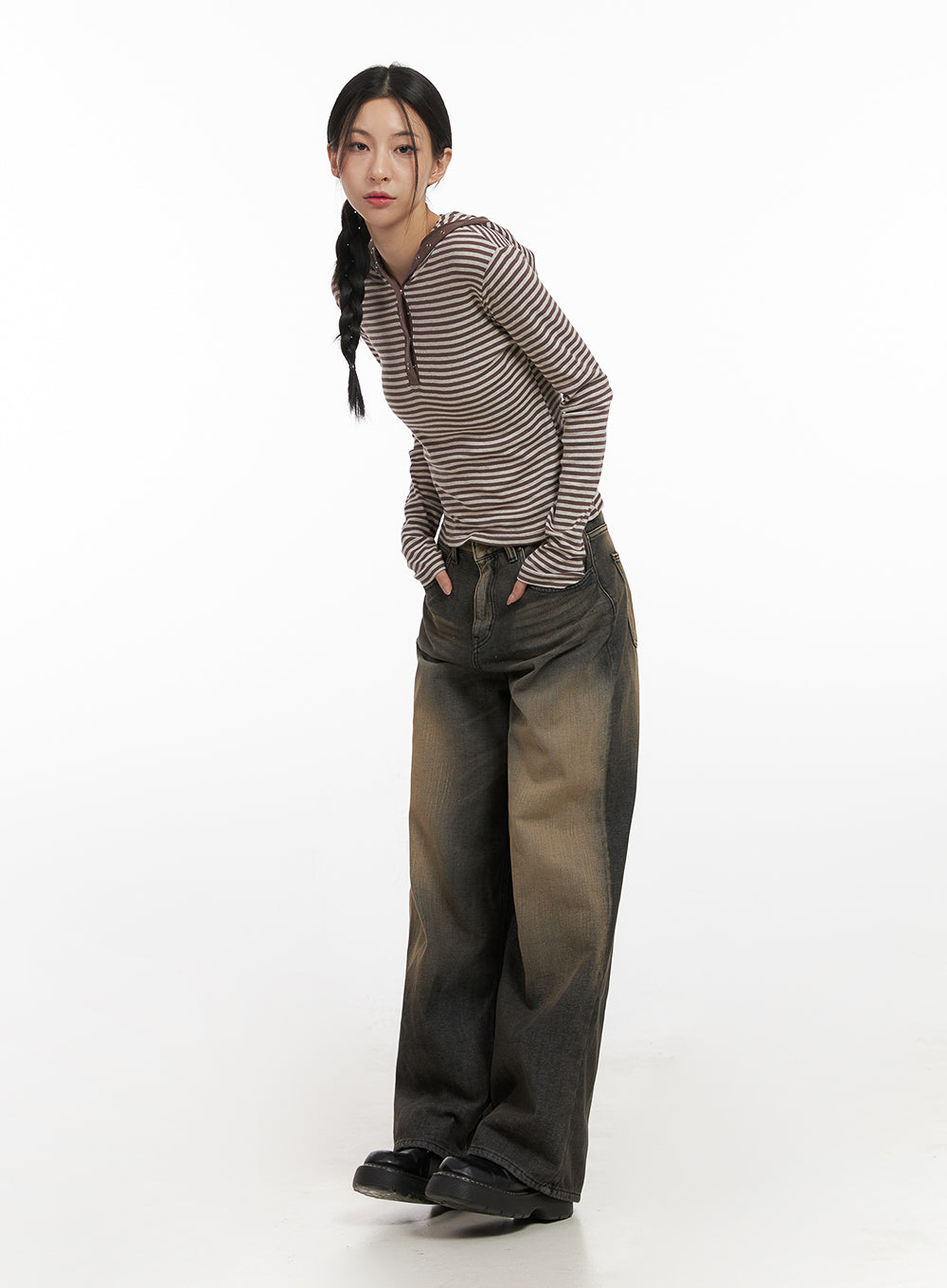 Alexa ComfyChic Washed Jeans CN428 in dark beige, three-quarter angled view on model leaning forward, baggy wide-leg washed denim with golden-brown fade, styled with striped hoodie and black loafers.