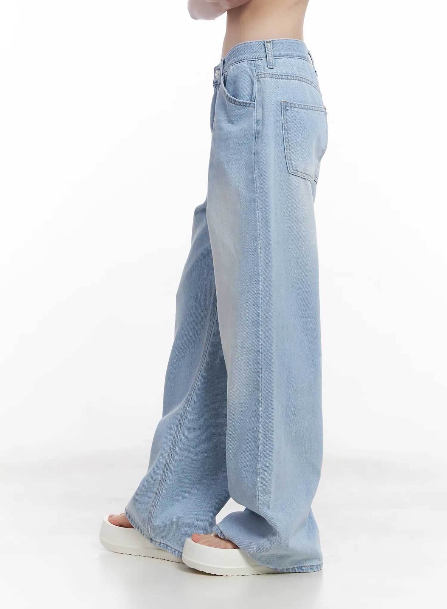 Haerin Washed Wide-Leg Jeans CU519 in light blue, rear three-quarter close-up on model, back patch pocket detail and side seam visible, washed cotton denim, no top shown.