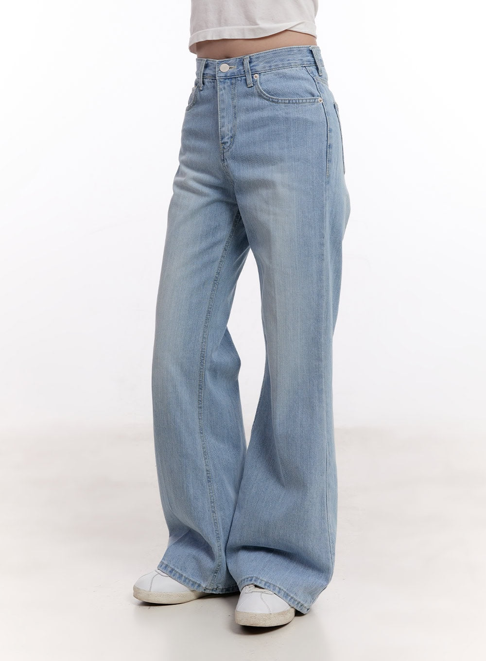Daniella Relaxed-Fit Flared Jeans CM526 in light blue, side-angle product shot on model, showing high-rise waist, side seam detail, and flared hem sweep over white sneakers.