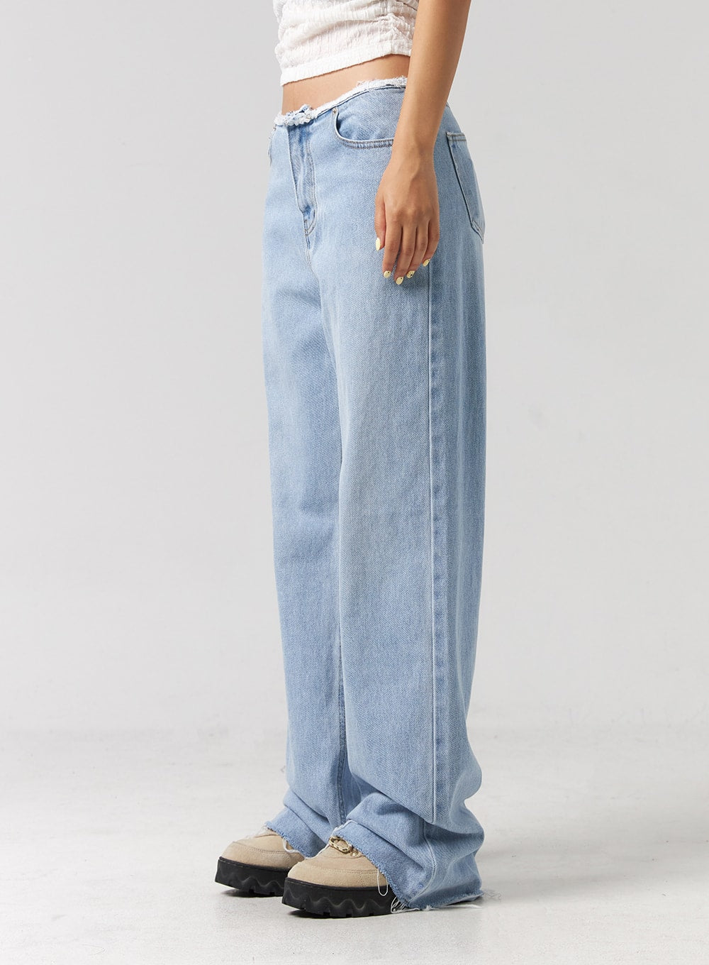 Cut Waist Wide Leg Jeans CG323 in light blue, side view close-up on model, wide-leg cotton denim with frayed cut waist and raw-hem hem, floor-grazing length visible.
