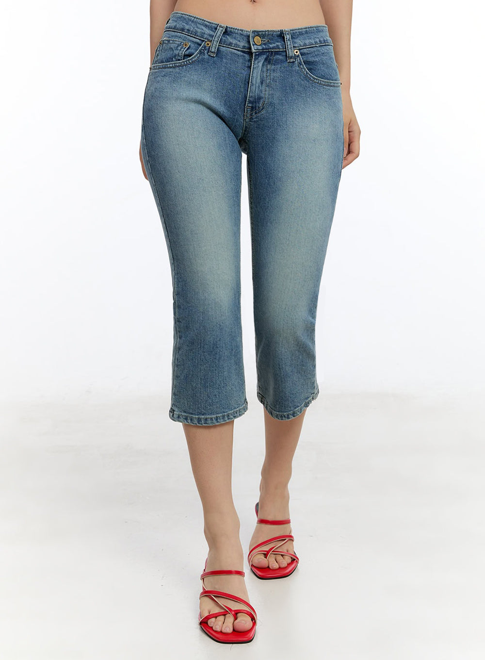 Kyra Cropped Low-Rise Skinny Jeans IU503 in blue, front mid-shot on model, washed cotton-polyester denim, low-rise five-pocket cut with cropped straight hem, worn with red strappy heeled mules.