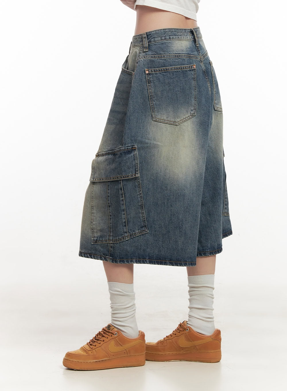 Cargo Bermuda Denim Shorts CF514 in dark blue, side view on model from waist down, midi length with large cargo flap pocket and back hip pocket, washed denim, with tan sneakers.