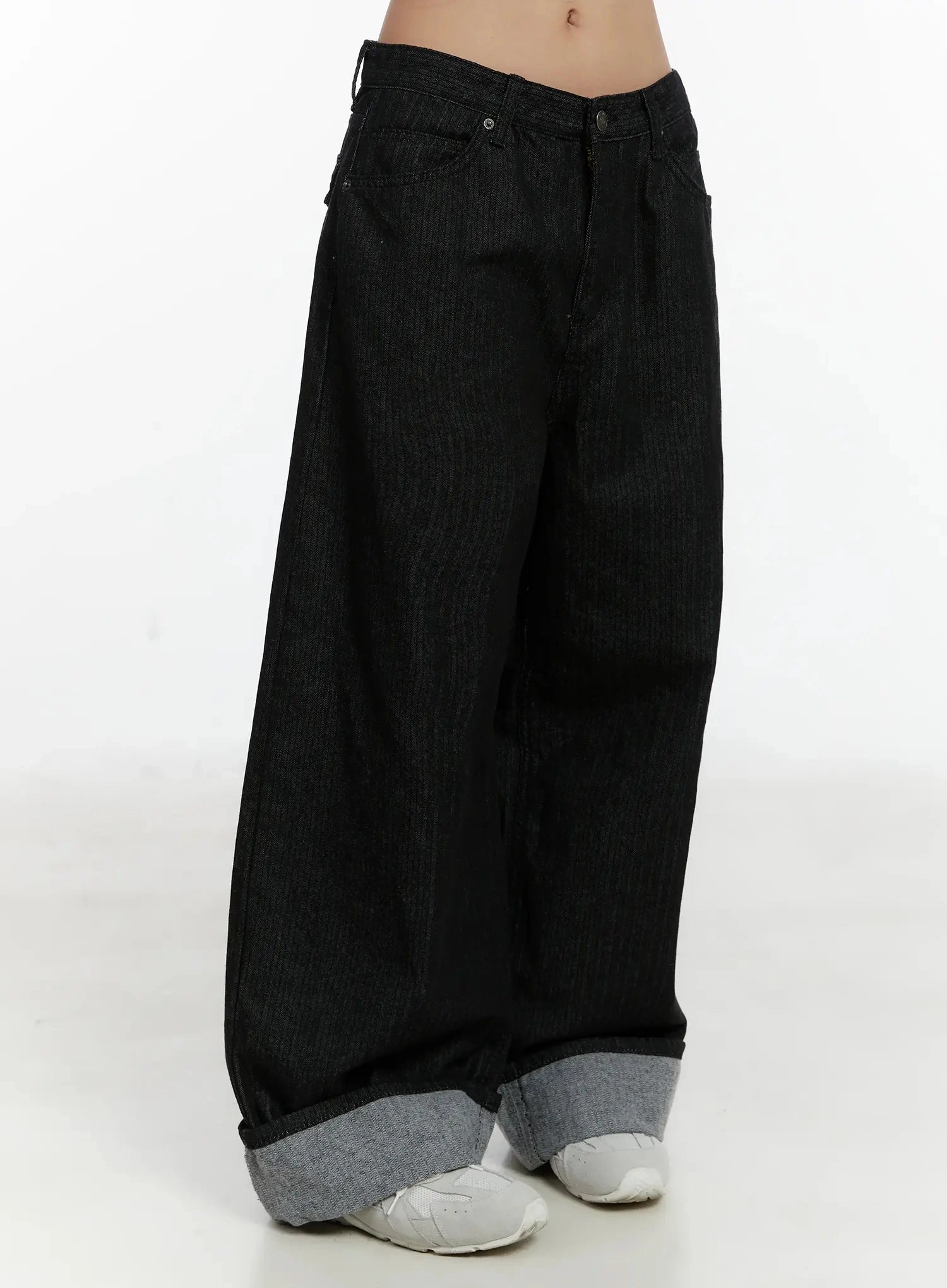 Amyra Baggy Striped Jeans ID525 in black, side view on model, low-rise wide-fit cotton denim with voluminous leg, contrast grey cuffed hem pooling over white sneakers.