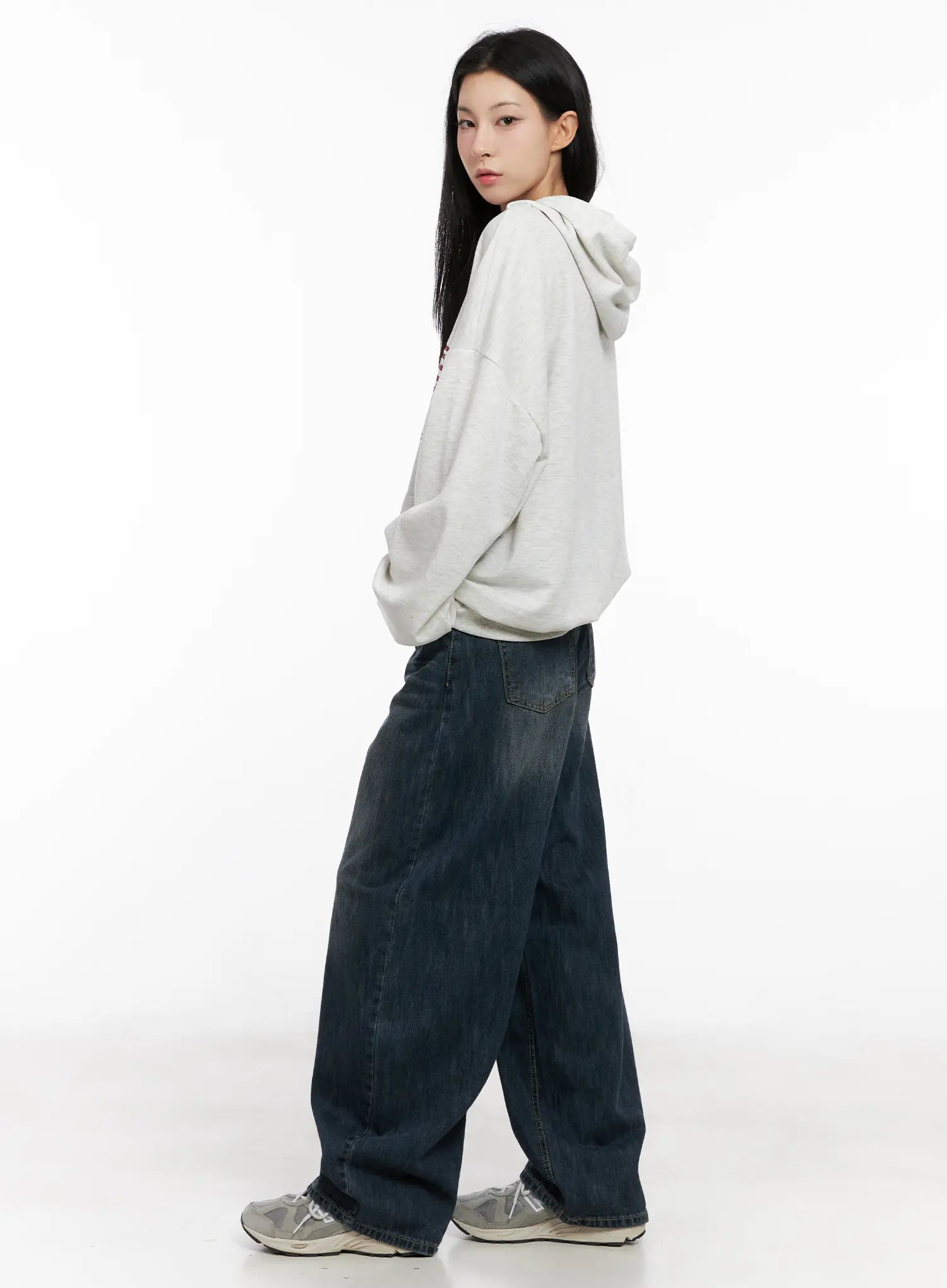 Seoy Washed Denim Jeans CG525 in dark blue, side full-length shot on model walking, wide balloon leg pooling at hem, paired with grey hoodie and chunky sneakers.