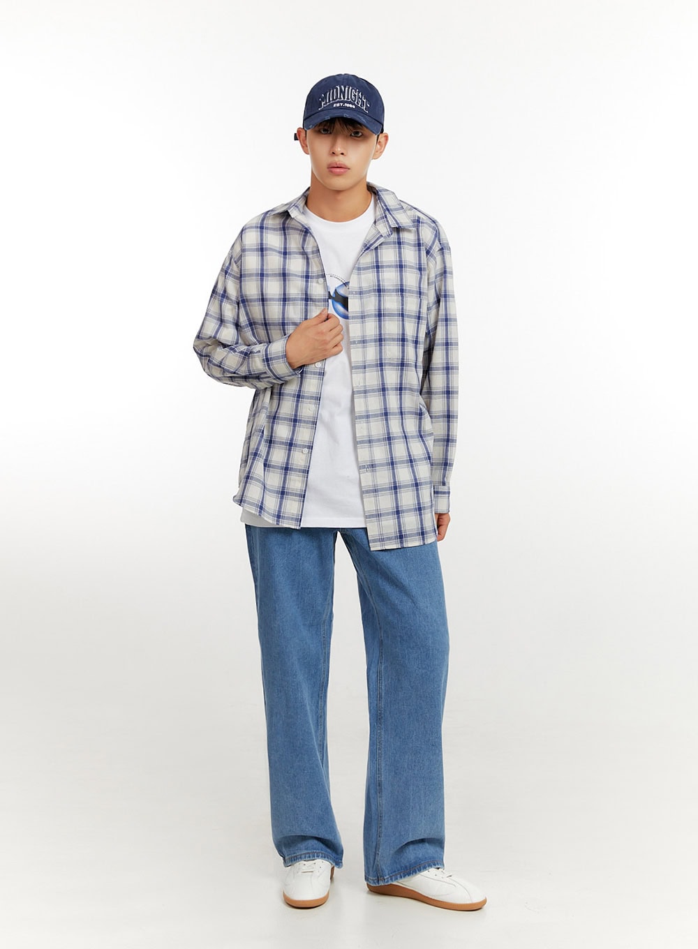 Men's Baggy Jeans (Blue) IU427 in blue, full-body front shot on model, relaxed wide-leg denim styled with open plaid shirt, graphic tee, cap, and white sneakers.