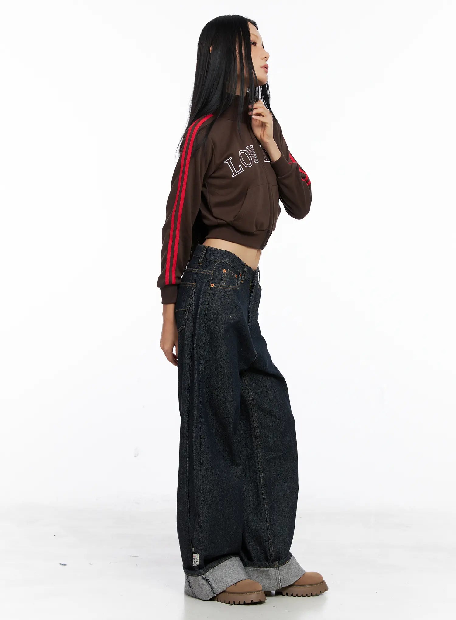 Oakley Cuffed Wide-Leg Jeans CS511 in dark blue, side full-length shot on model in profile, oversized wide-leg drape visible, grey contrast roll-up cuff at hem, paired with brown crop jacket.