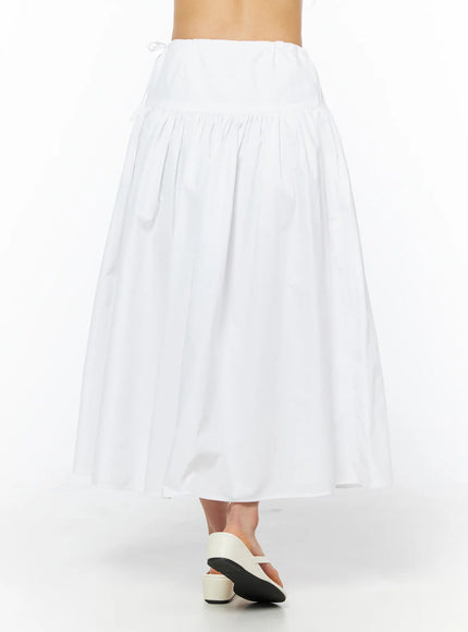 Basic Ribbon Maxi Skirt CU522 in white, back view on model from waist to hem, gathered elastic waistband with side ribbon tie, voluminous cotton maxi flare, white sandals.