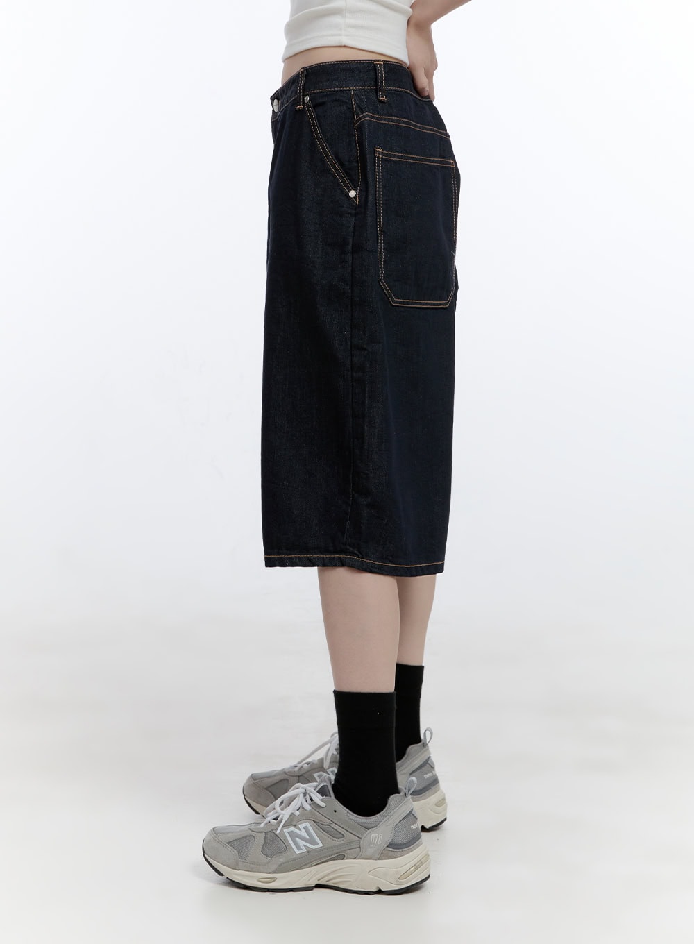 Dora Stitched Baggy Jorts CG413 in dark blue, side close-up on model, highlighting patch side pocket and golden contrast topstitching on dark indigo cotton denim.