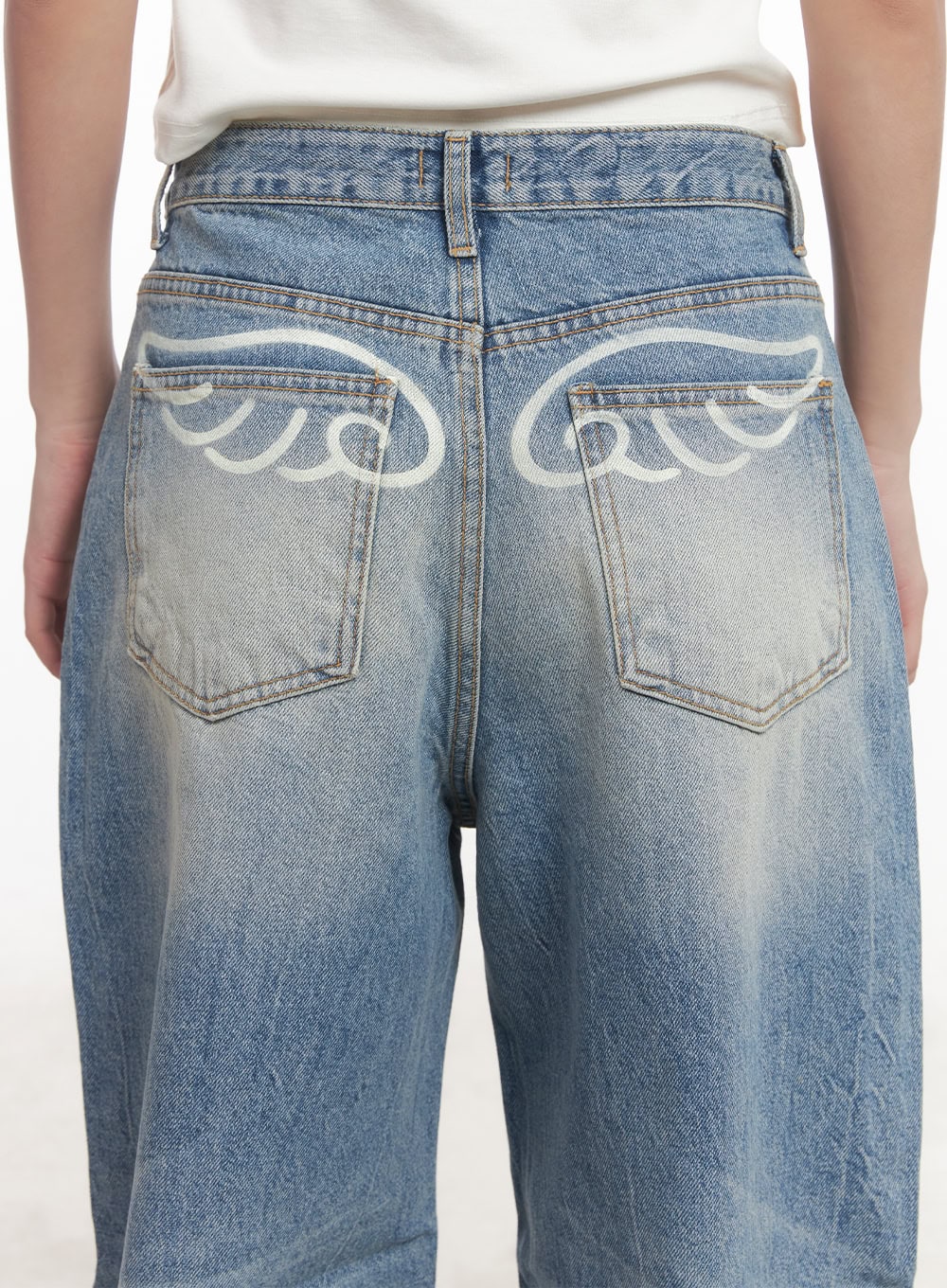 Lumira Back-Detail Washed Wide Leg Jeans CA530 in blue, close-up back detail shot, white angel wing graphic print spanning both back pockets on washed cotton denim.