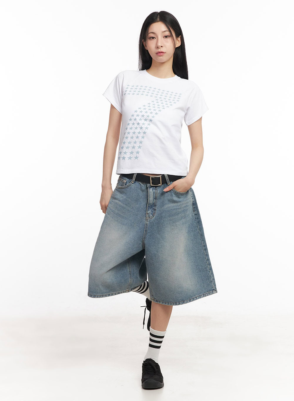 Washed Baggy Jorts IY529 in light blue, full-body front shot on model, wide-fit midi washed denim, one leg raised, styled with white star-print crop tee, black belt, and black sneakers.