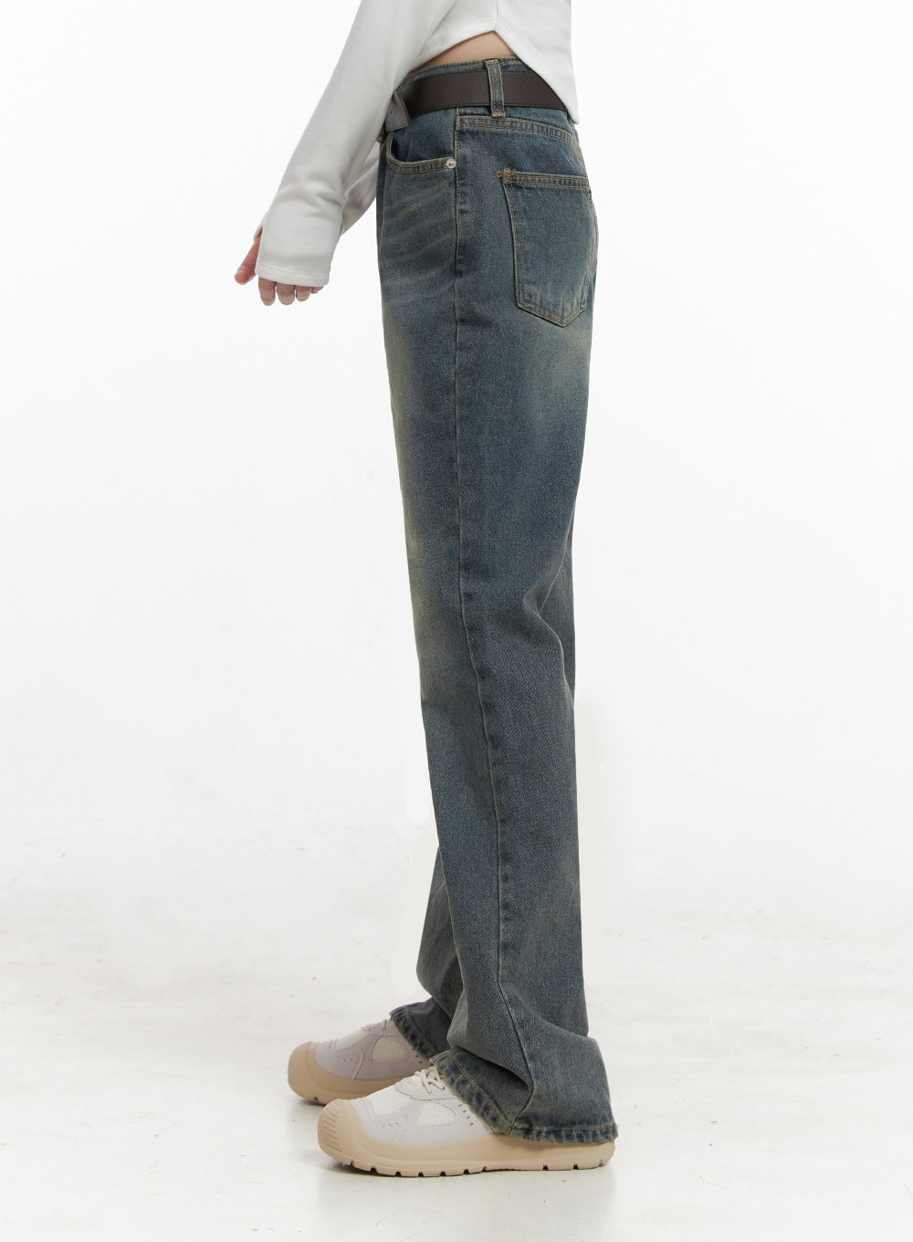 Asher Slimline Washed Bootcut Jeans ID402 in vintage blue, side-view close-up on model, slim through thigh with subtle bootcut flare, back pocket visible, worn with brown belt and white top.