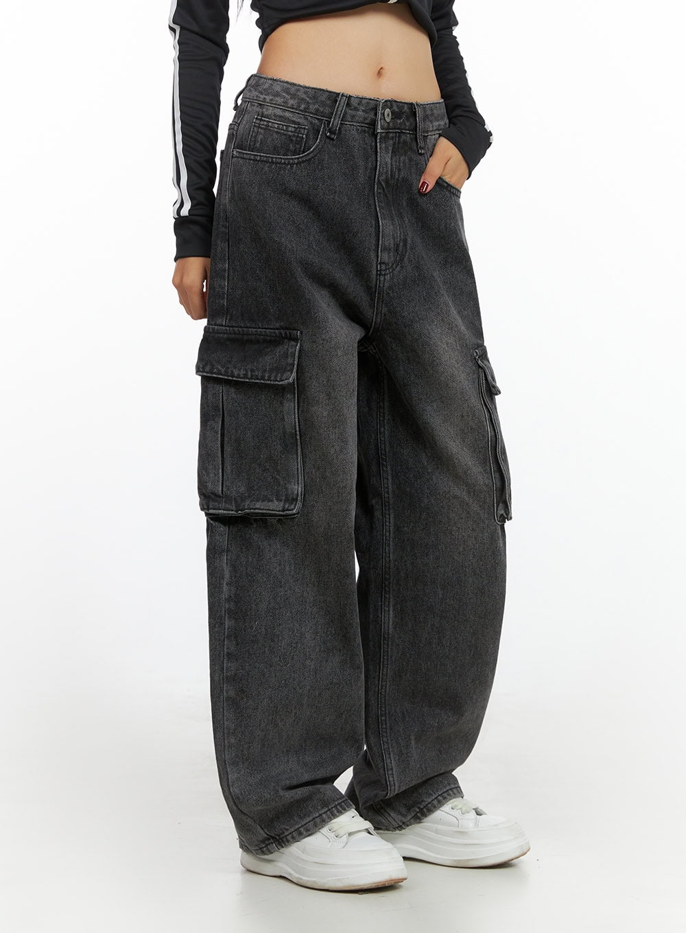Neve Washed Cargo Denim Jeans IS427 in washed black, side-angle waist-to-hem shot on model, highlighting stacked cargo pockets with flap closures and wide-fit baggy leg, with white sneakers.