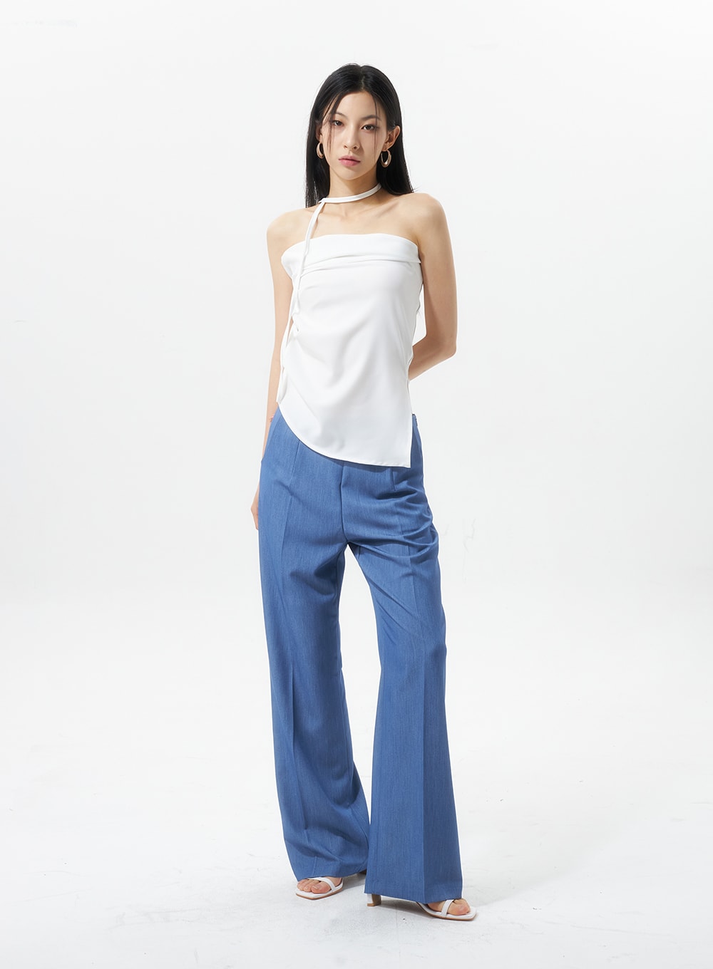 Low Rise Tailored Pants IU326 in blue, three-quarter front view on model, low-rise tailored silhouette with wide leg, paired with white asymmetric halter choker top and white sandals.