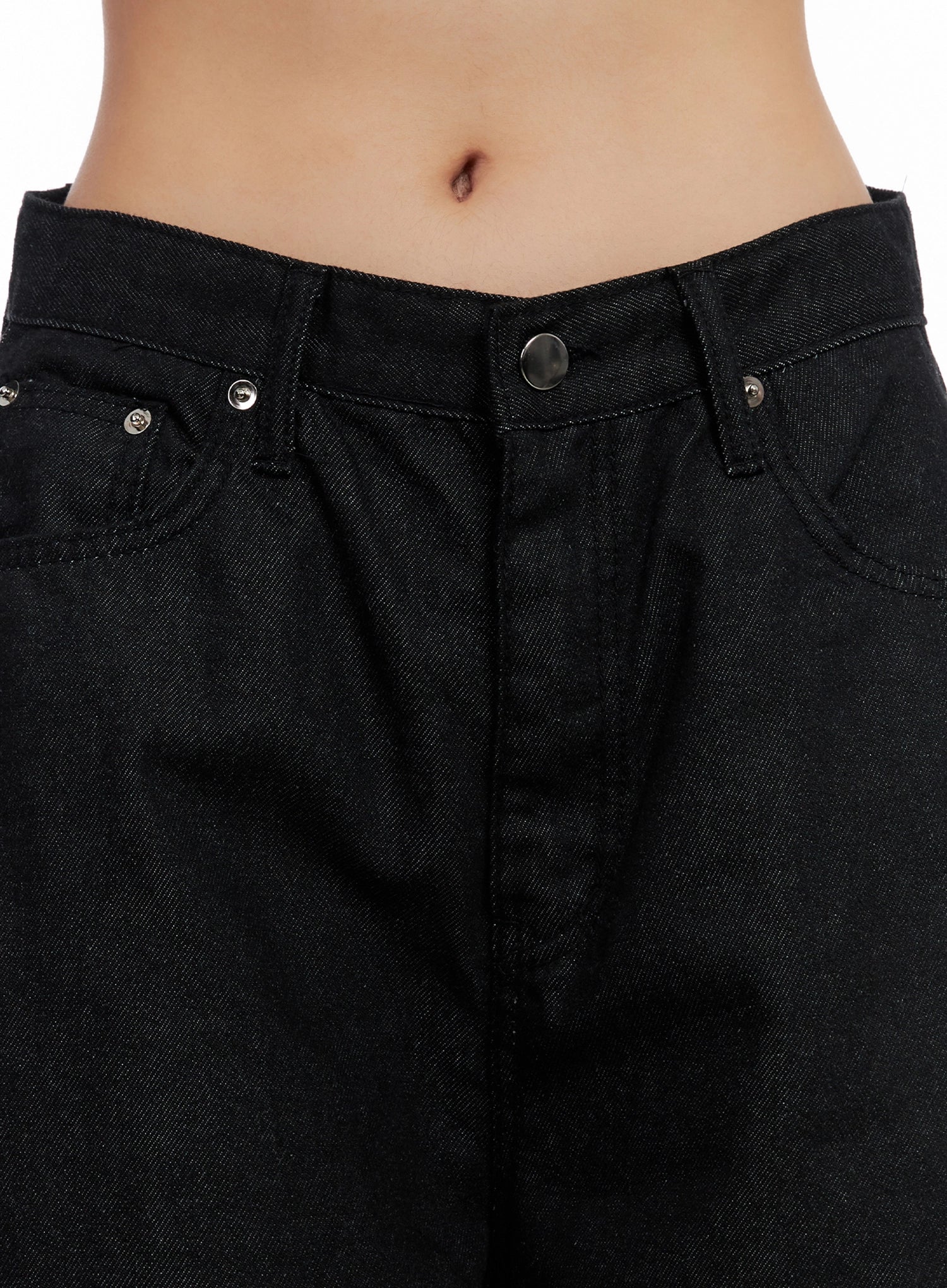 Lea Cross-Patch Baggy Jeans IS525 in black, close-up waistband detail on model, mid-rise button fly with silver rivets, five-pocket construction, cotton denim twill texture visible.