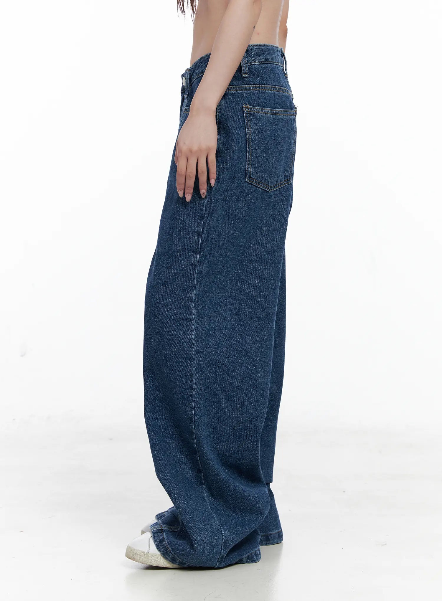 Eliza Seam Detail Relaxed Bootcut Jeans CO521 in washed blue, side view waist-to-floor on model, back pocket and vertical seam detail visible, wide-leg bootcut silhouette, white sneaker at hem.