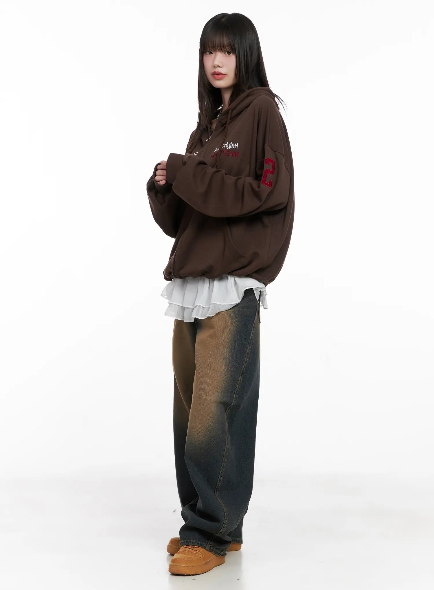 Jaycee Vintage Wash Baggy Jeans CG519 in dark blue, full-body side editorial on model, layered with brown hoodie and white ruffle top, showing long wide-leg length and tan sneakers.