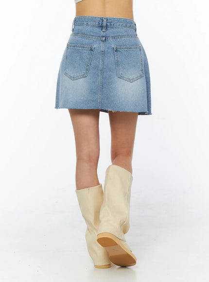 Casual Denim Mini Skirt CU522 in light blue, back view from waist down on model, dual back pockets, raw-cut hem, faded wash, paired with cream fold-over sandal boots.