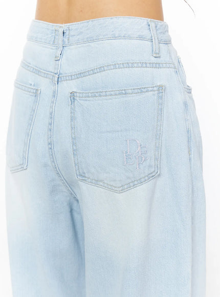 Rina Washed Wide-Leg Jeans CU522 in light blue, back close-up detail on model, highlighting rear pocket with embroidered logo and washed denim surface.