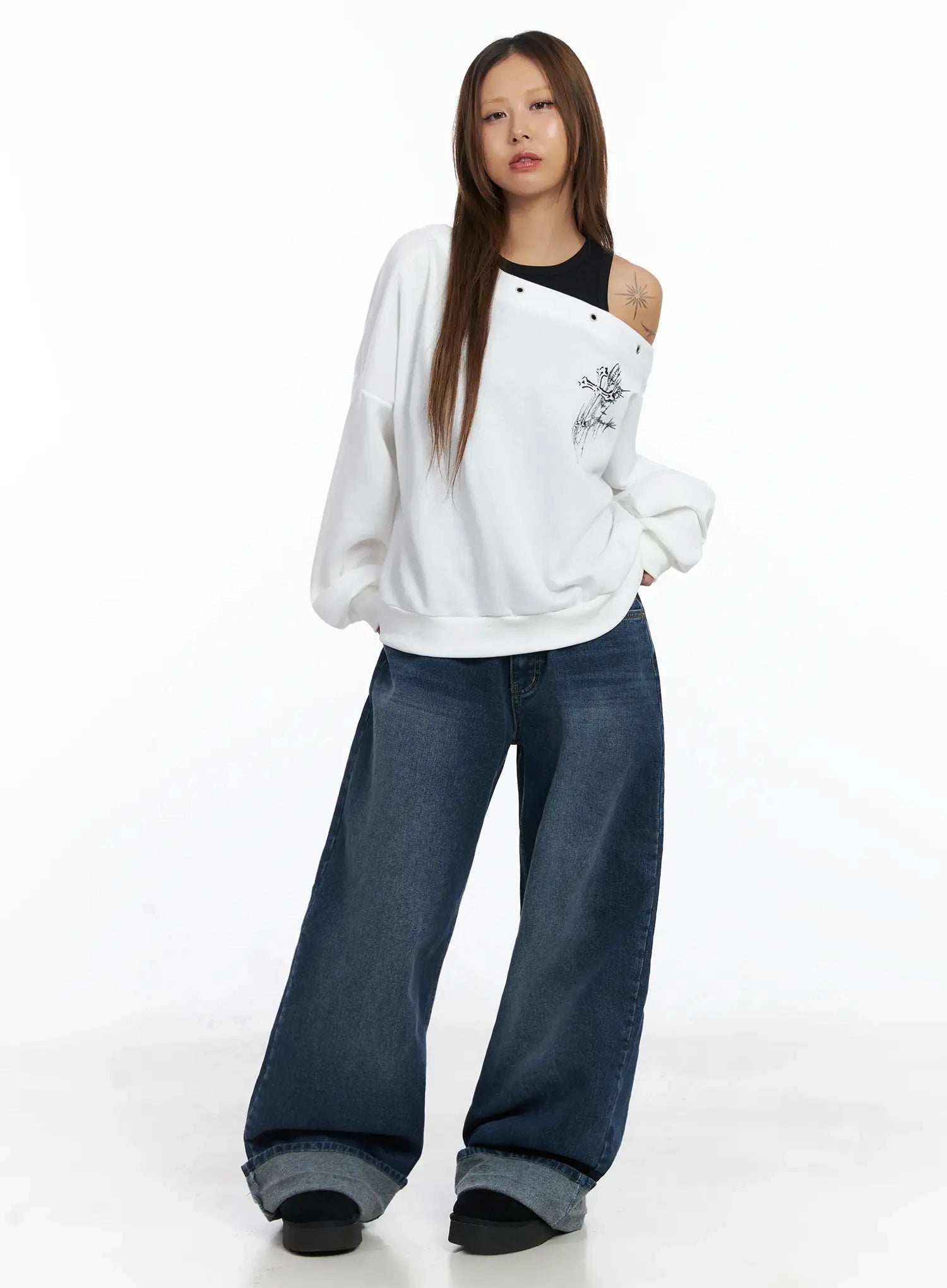 Anahi Baggy Jeans IN528 in blue, front full-length editorial on model, wide-leg with rolled cuff, paired with oversized white graphic sweatshirt and black tank.