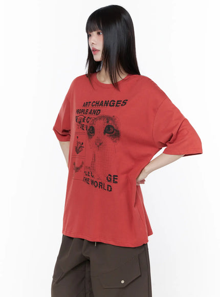Oversized Cat Print Graphic Tee CU519 in dark red, front angled close-up on model with hand on hip, showcasing halftone cat face and 'Art Changes The World' slogan graphic detail on cotton tee.