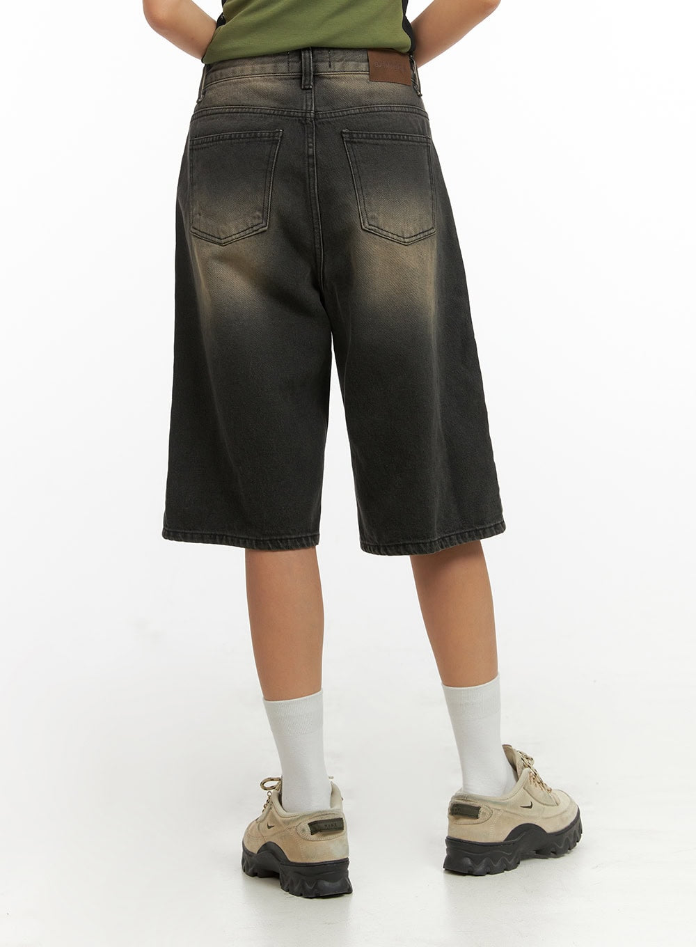 Color Washed Jorts IY422 in black washed denim, back view on model, two back pockets with brown leather patch, gradient color-washed cotton denim, wide-leg knee-length cut.