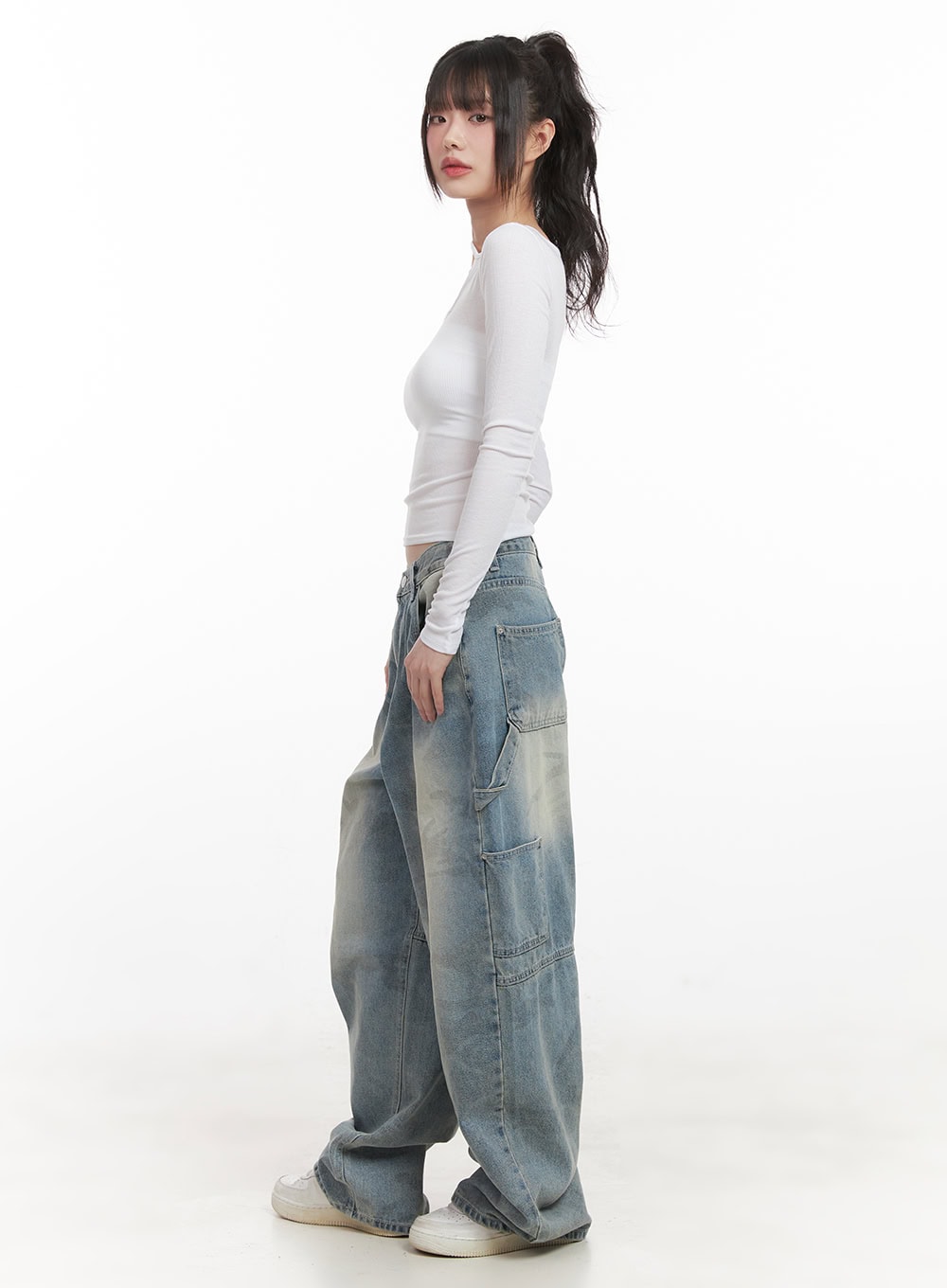 Abigail Camo-Print Carpenter Baggy Jeans CJ528 in blue, side full-body shot on model looking back, baggy washed camo denim with side cargo pockets, paired with white fitted long-sleeve top.