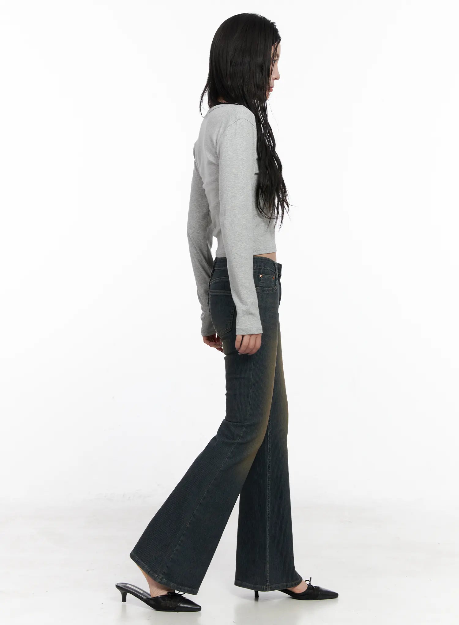 Soleil Hip Pad Stripe Hip Pad Flared Jeans CN512 in dark blue, side walking pose on model, washed stripe bootcut with visible flare from knee, long length, paired with gray crop top and black bow kitten-heel mules.