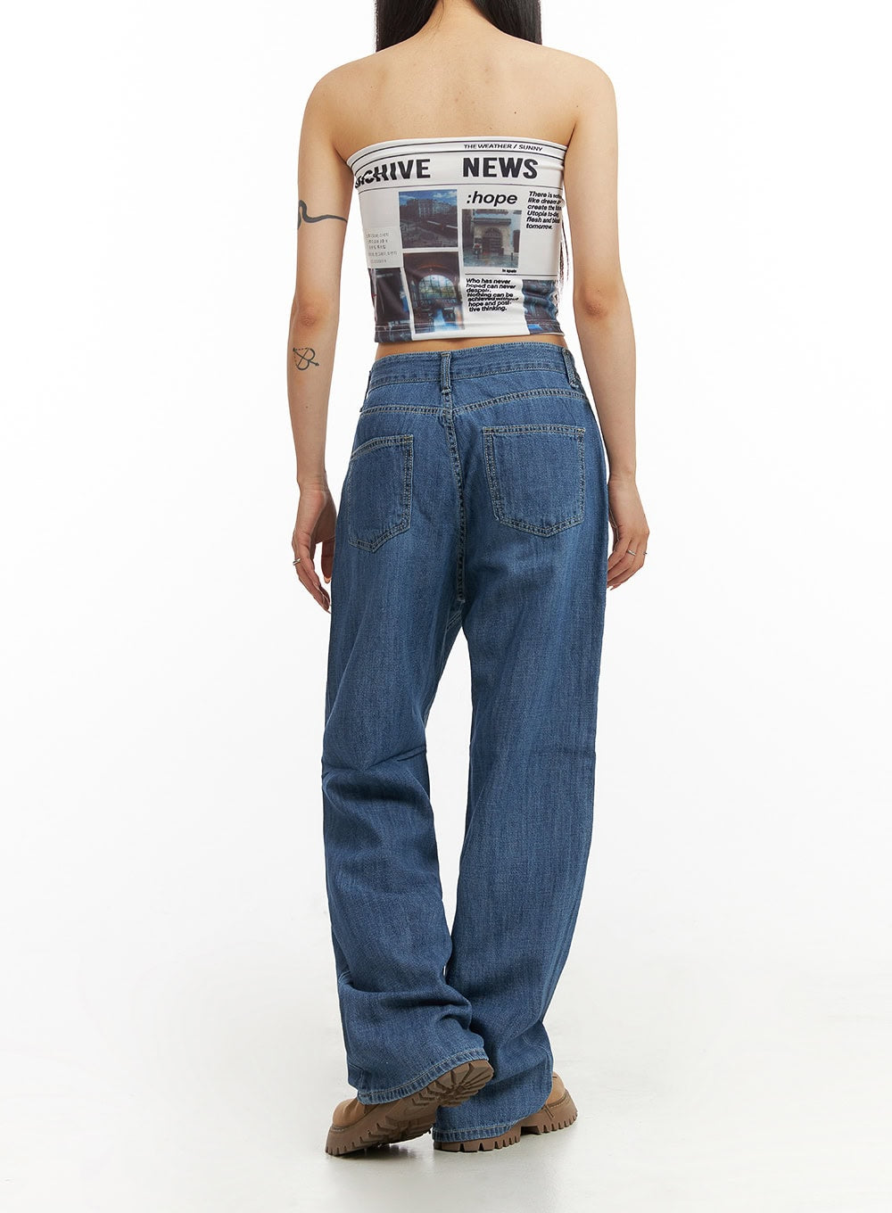 Solid Low Rise Baggy Jeans CY407 in blue, back close-up on model, patch pockets and low-rise waistband detail visible, wide-leg washed denim with graphic bandeau top and tan boots.
