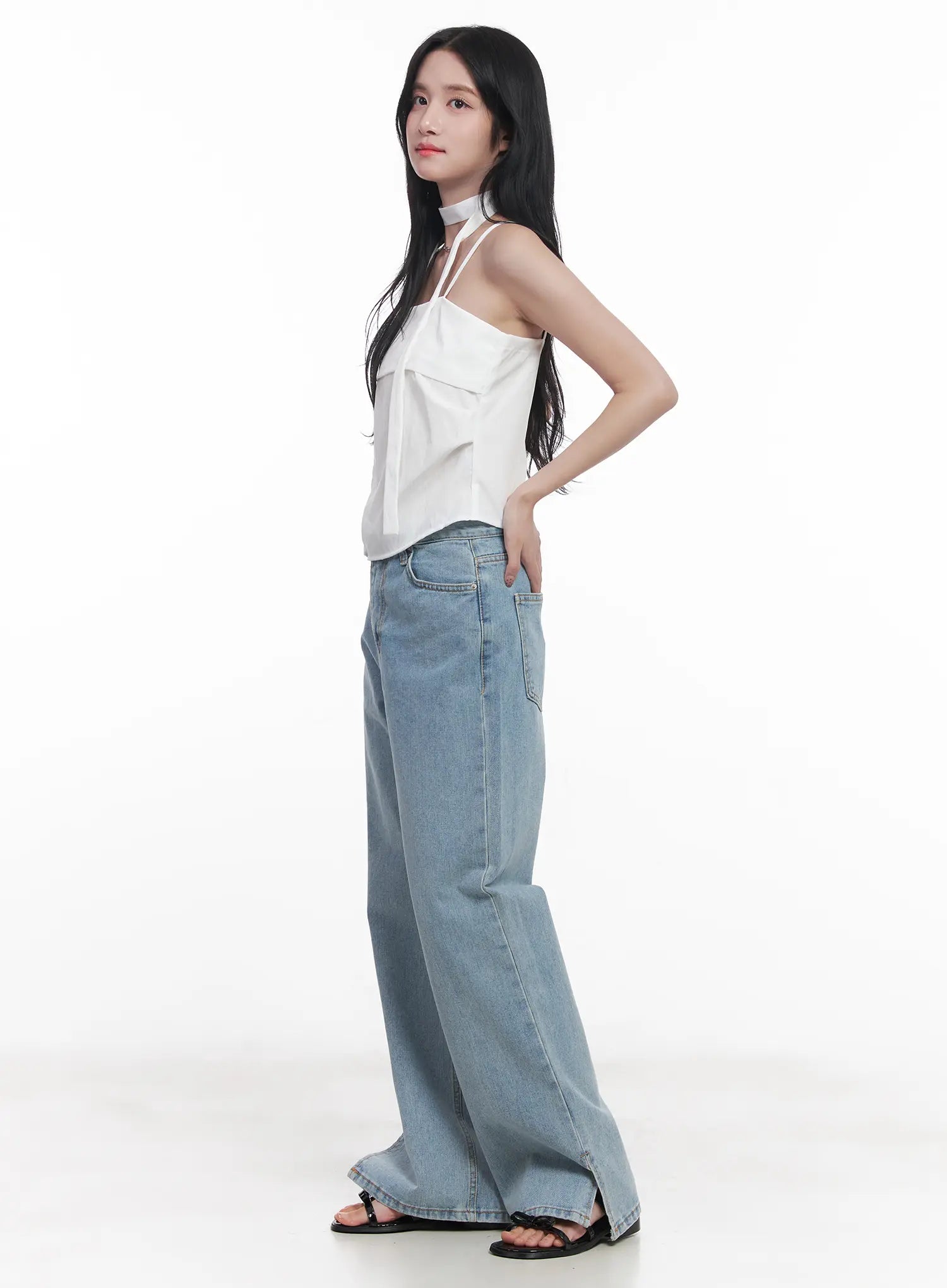 Hyuna Slit Straight-Fit Jeans CU525 in light blue, three-quarter side view on model hand on hip, wide-fit washed denim with front seam and hem slit, styled with white halter top.