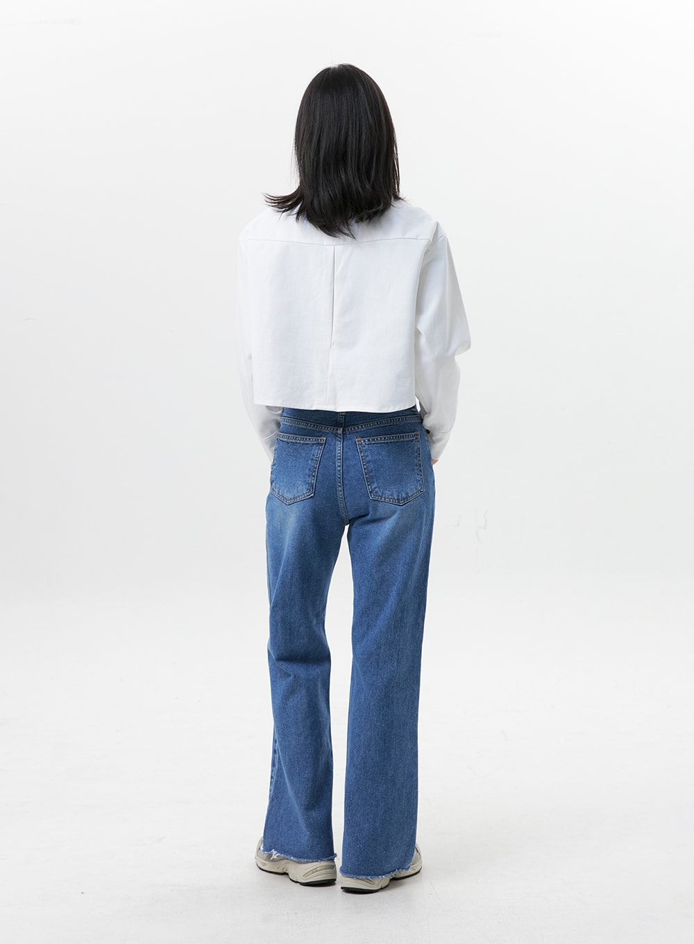 Straight-Leg Jeans OG318 in medium blue, back full-length on model, two back patch pockets visible, straight-leg cotton denim with slight flare at hem, raw frayed hem detail.