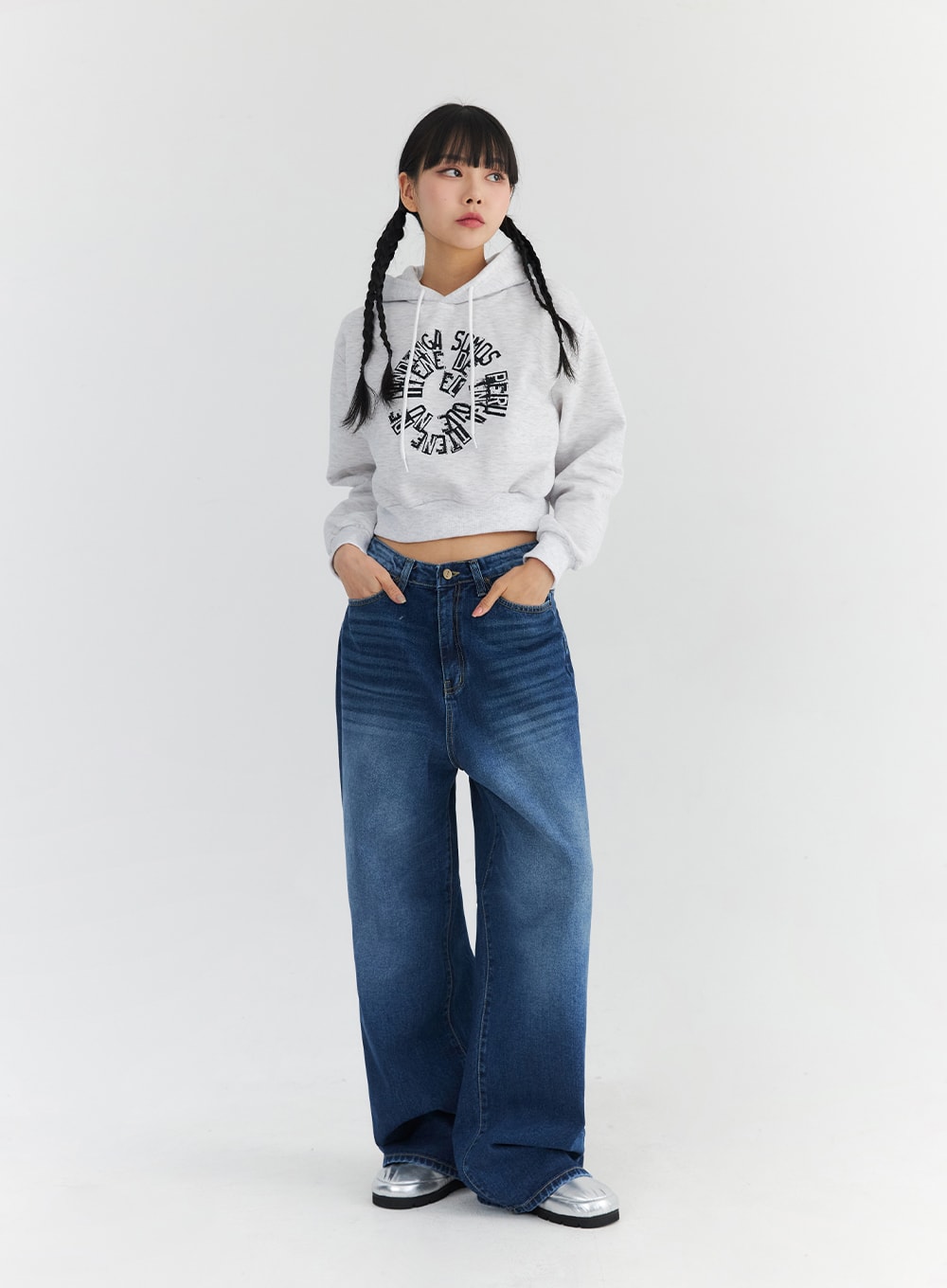 Washed Blue Wide Jeans CN301 in blue, full-length front editorial shot on model looking up, wide-fit washed denim with hands in pockets, paired with grey crop hoodie and silver shoes.