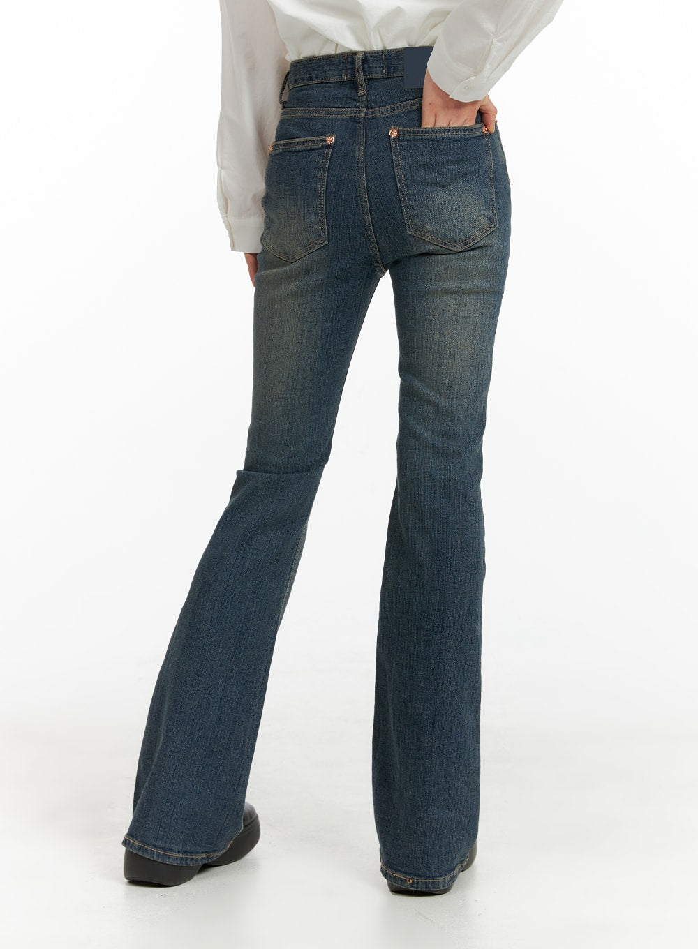 Washed Flared Jeans CM413 in blue, back view on model, showing rear pockets with rose-gold rivets, high-rise waist, and wide flared hem, paired with white shirt.