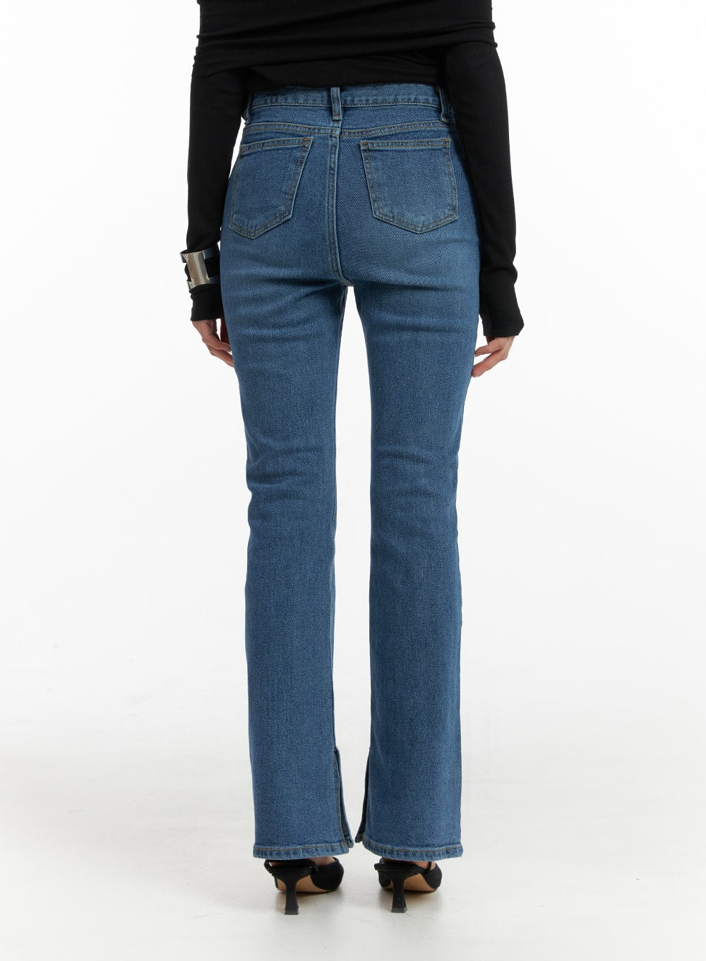 Vintage Flared Jeans IM414 in blue, back view on model, five-pocket washed denim with dual back pockets and hem slit, worn with black long-sleeve top and kitten heels.