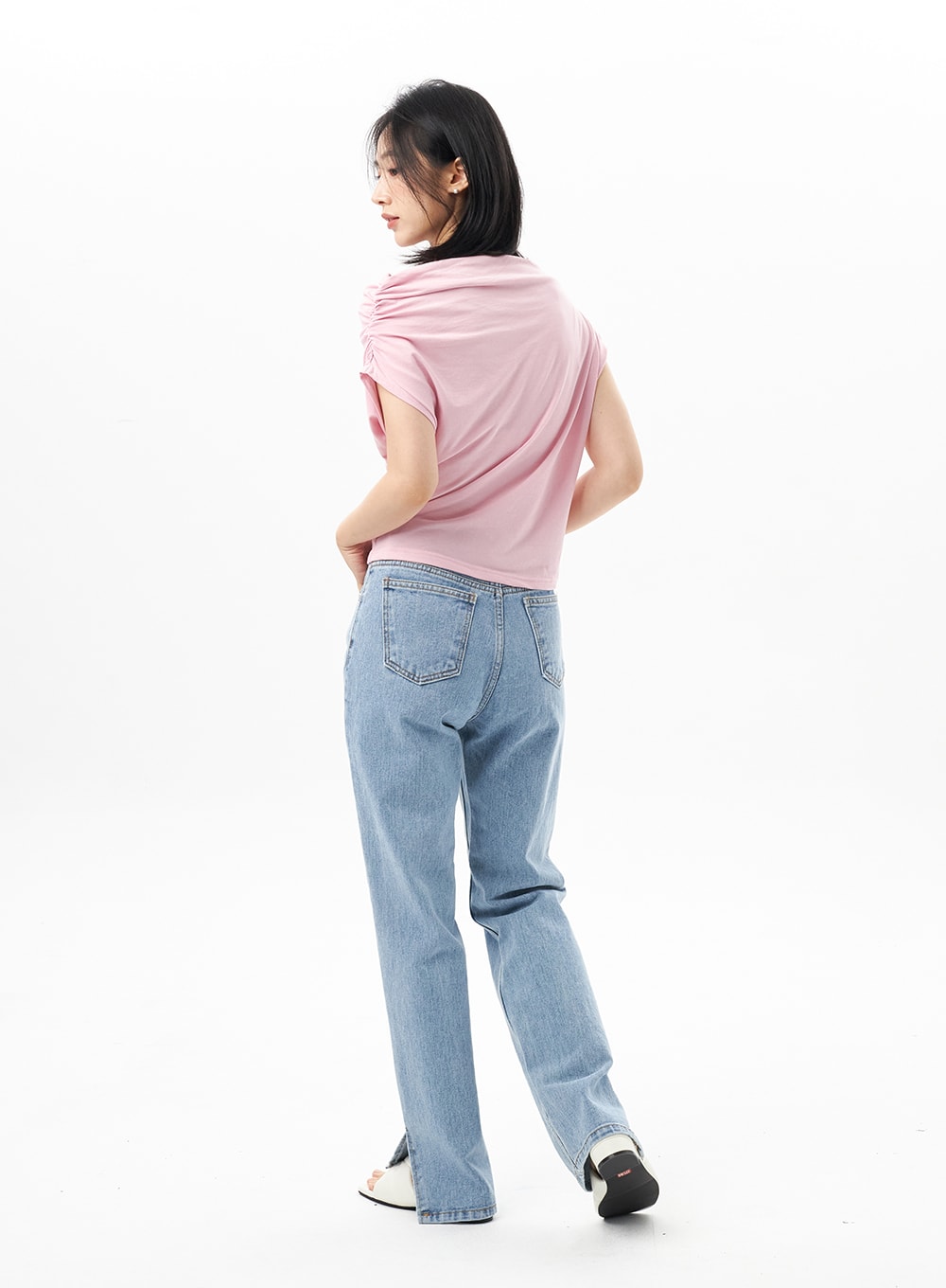 Slit Detail Jeans OU314 in blue, back three-quarter view on model stepping forward, hem slit visible at both ankles, high-waist straight denim, styled with pink top.