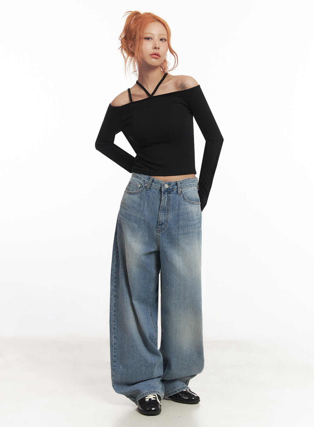 Yvette Washed Baggy Jeans IA517 in light blue, full-length front view on model, wide baggy fit with subtle whiskering, low rise, paired with black off-shoulder long-sleeve crop top and black patent loafers.